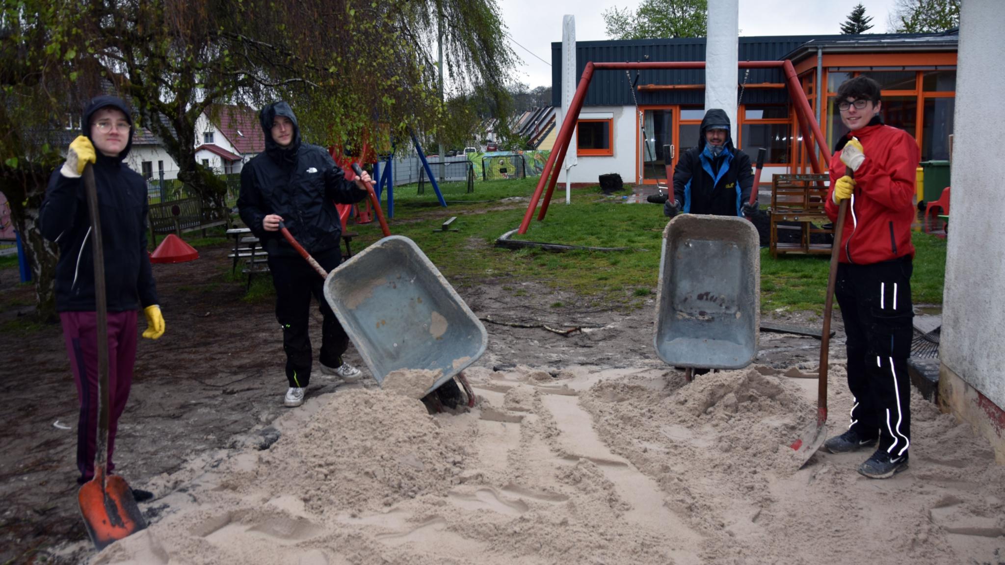 Mit Schubkarren und Schaufeln befüllen Justin, Valentin, Luca und Yannik (vlnr) den Sandkasten der Kita St. Josef mit gespendetem Sand.