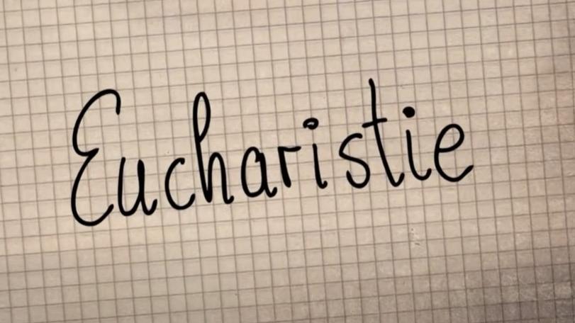 Auf ein kariertes Blatt Papier ist das Wort Eucharistie geschrieben