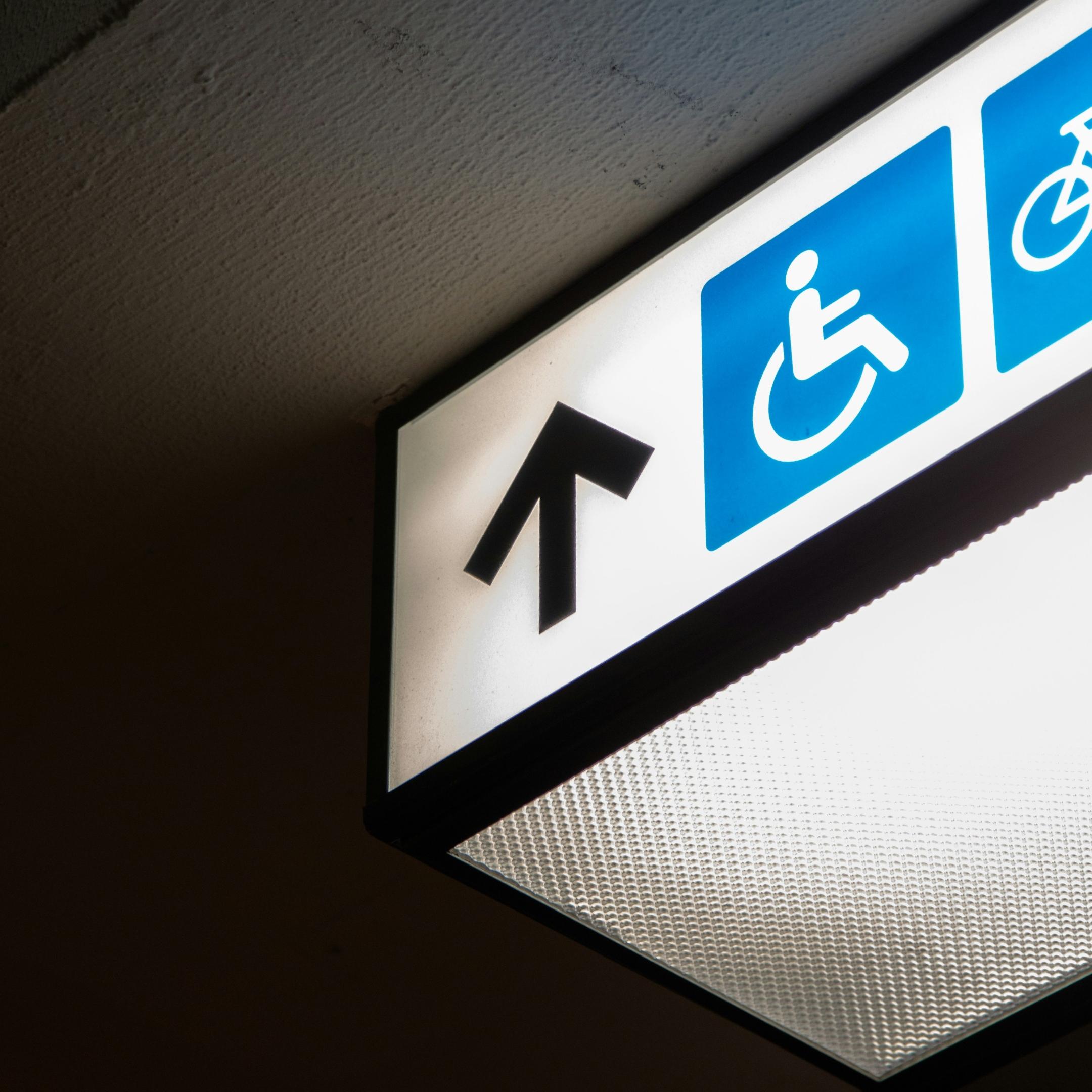 Hinweisschild Barrierefreiheit für Menschen mit Mobilitätseinschränkungen, Symbolbild Rollstuhlfahrer auf blauem Hintergrund