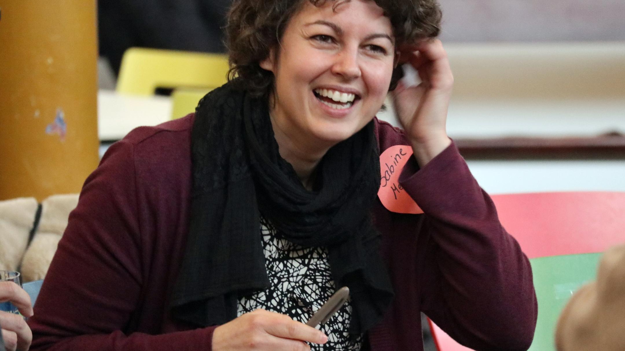 Eine junge Frau mit Locken schaut in die Kamera.