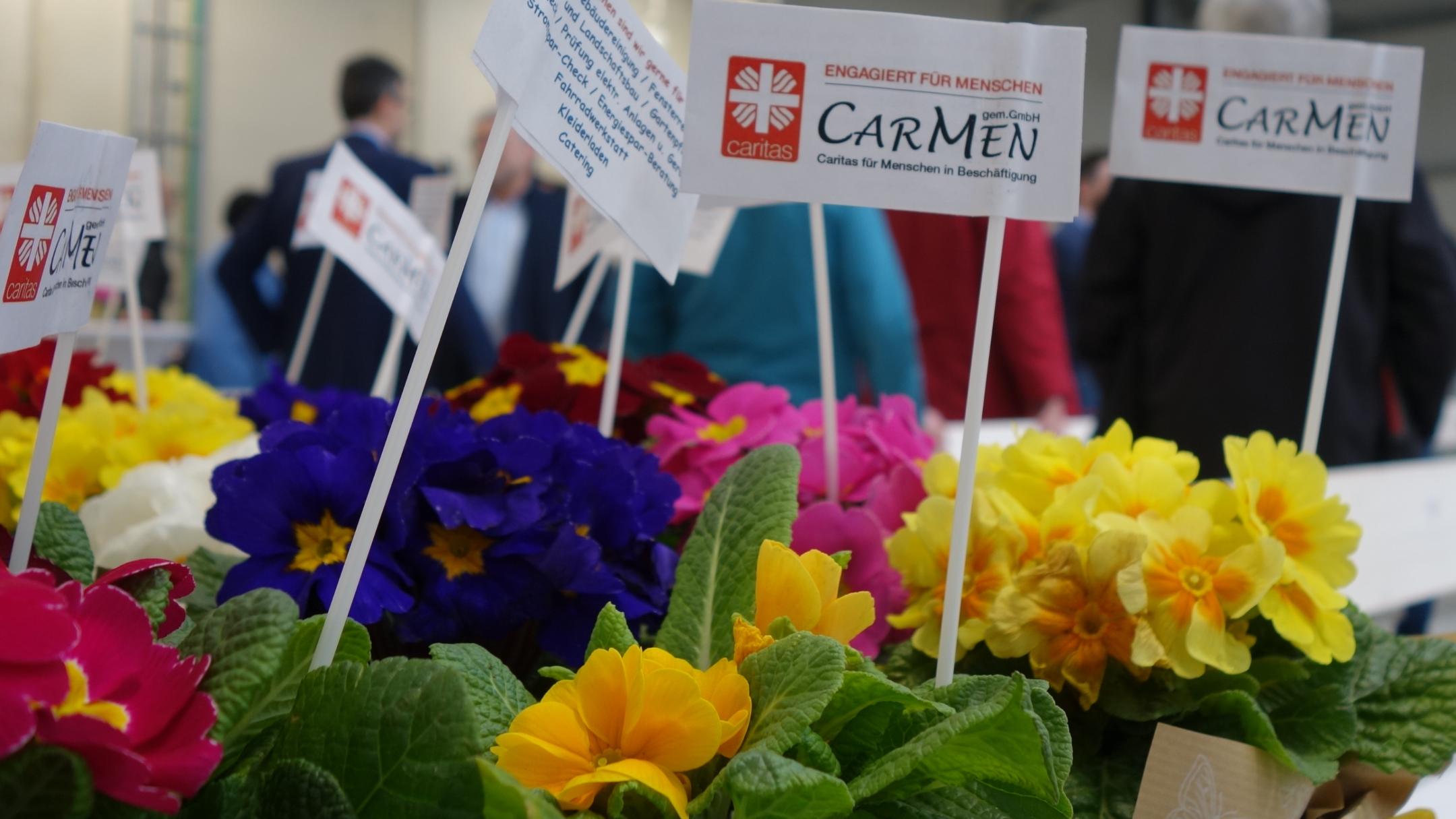 Blumen stehen auf einem Tisch, darin Zettel auf denen CarMen gGmbH steht.