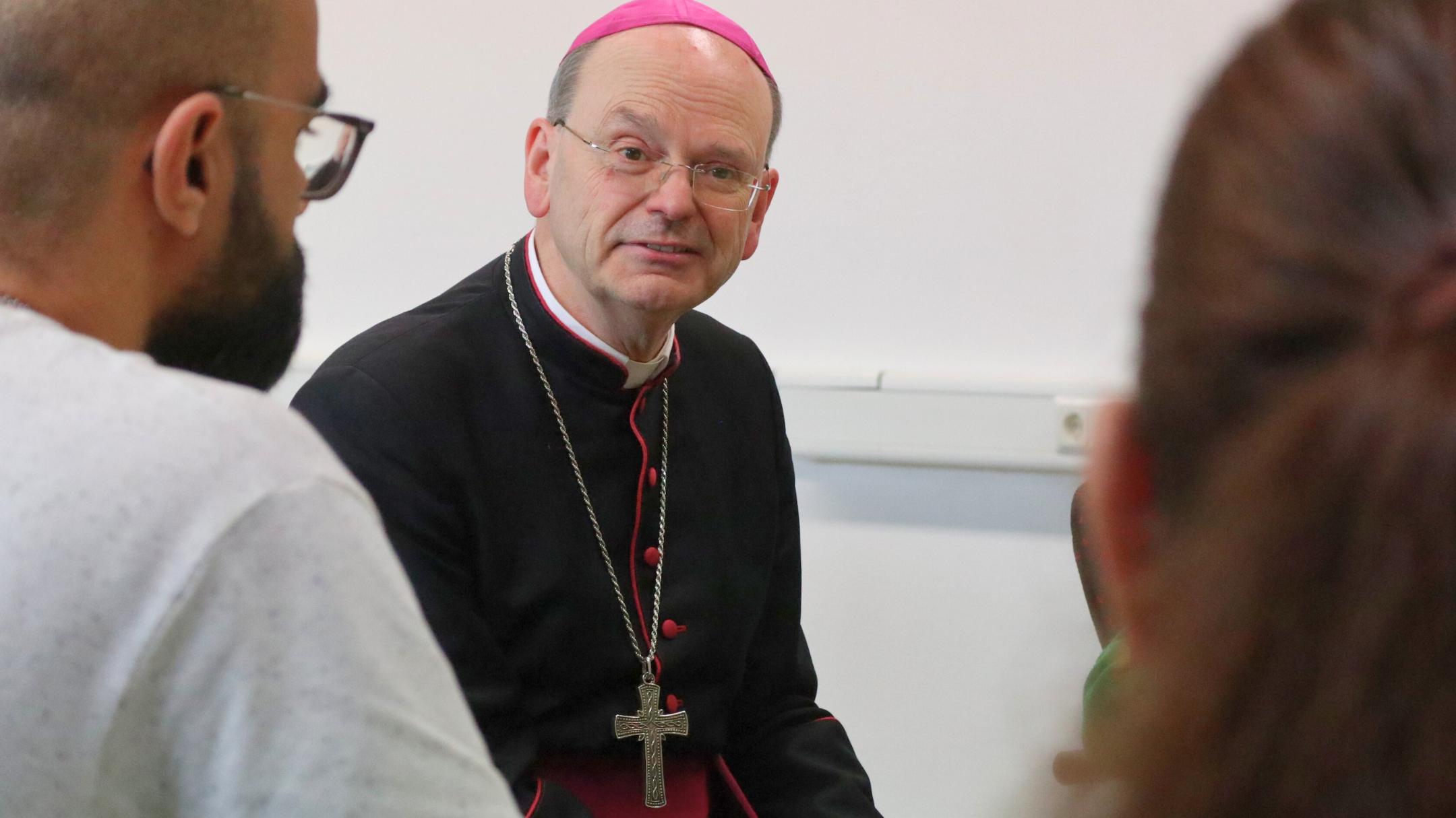 Weihbischof Robert Brahm tauscht sich mit Teilnehmenden eines Sprachkurses des Caritasverbands Rhein-Wied-Sieg in Betzdorf aus.