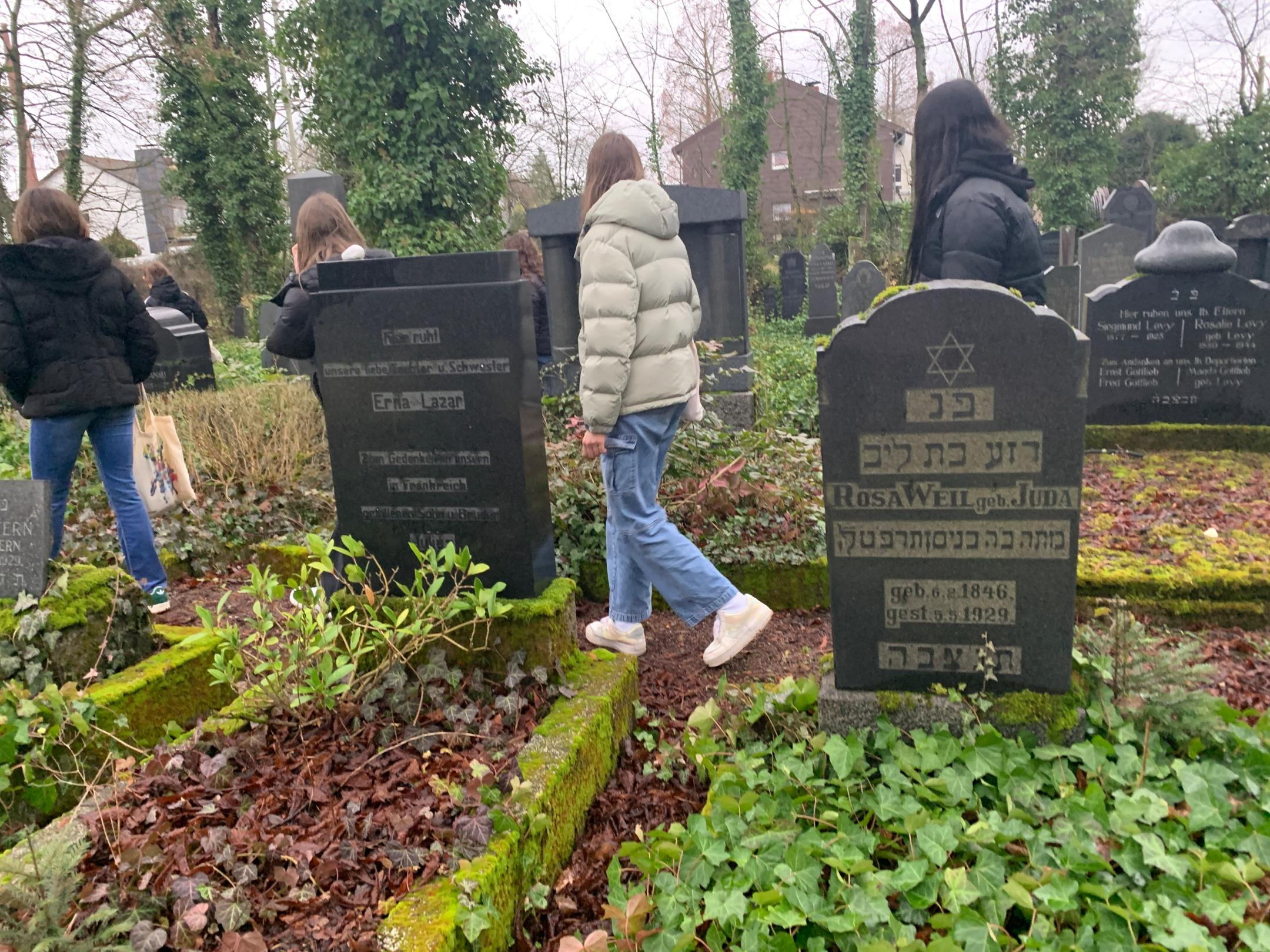 Schülerinnen und Schüler legen Steine auf jüdischen Gräbern in Saarlouis nieder.
