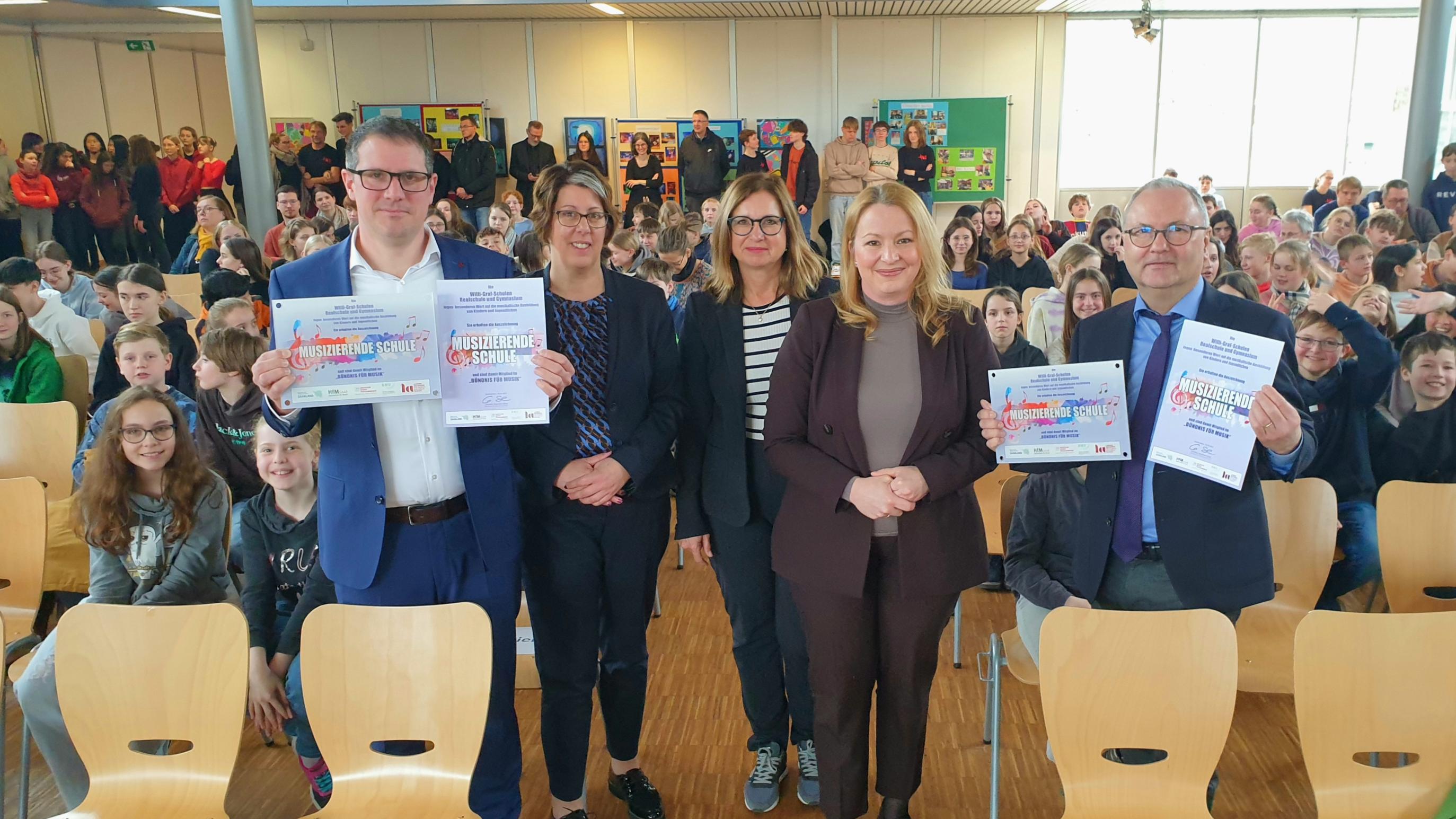 Freuten sich über die Auszeichnung der Willi-Graf-Schulen als 'Musizierende Schulen': Stephan Arnold (Schulleiter Realschule), Kerstin Schmitz (Leiterin des Arbeitsbereich Katholische Schulen im Bischöflichen Generalvikariat), Eva Kieser (Vizepräsidentin des Bundesverbandes für Musikunterricht und Projektleiterin zur Ausbildung der Musikmentoren in der Landesakademie in Ottweiler), Christine Streichert-Clivot (Ministerin für Bildung und Kultur des Saarlandes) und Stefan Kilz (Leiter des Gymnasiums)