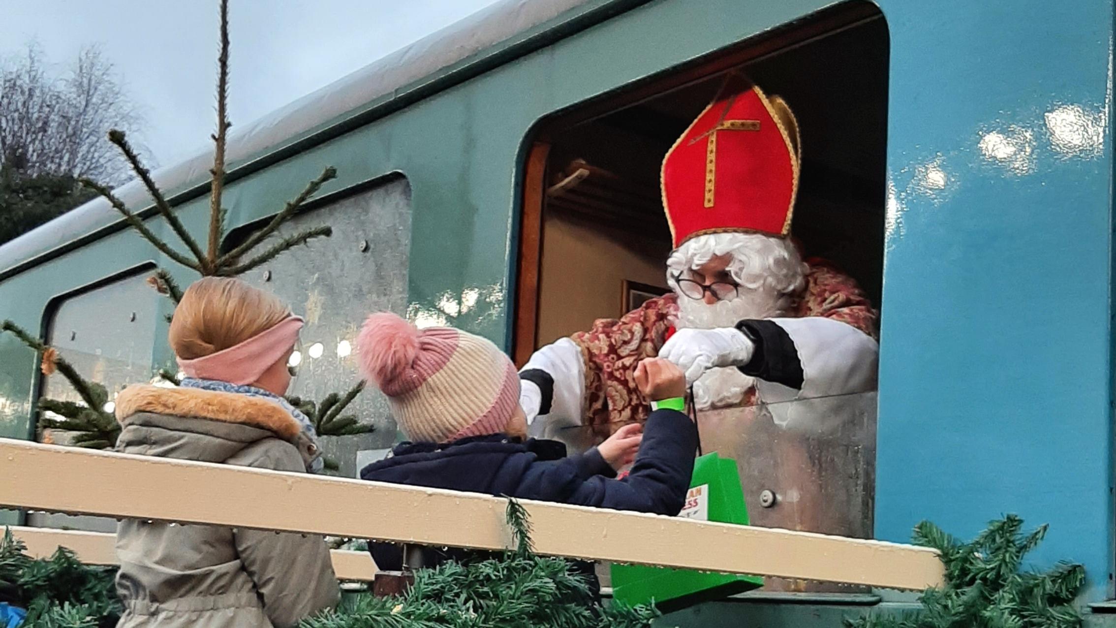 Niklaus verteilt Süßigkeiten aus einem Bahnfenster heraus.