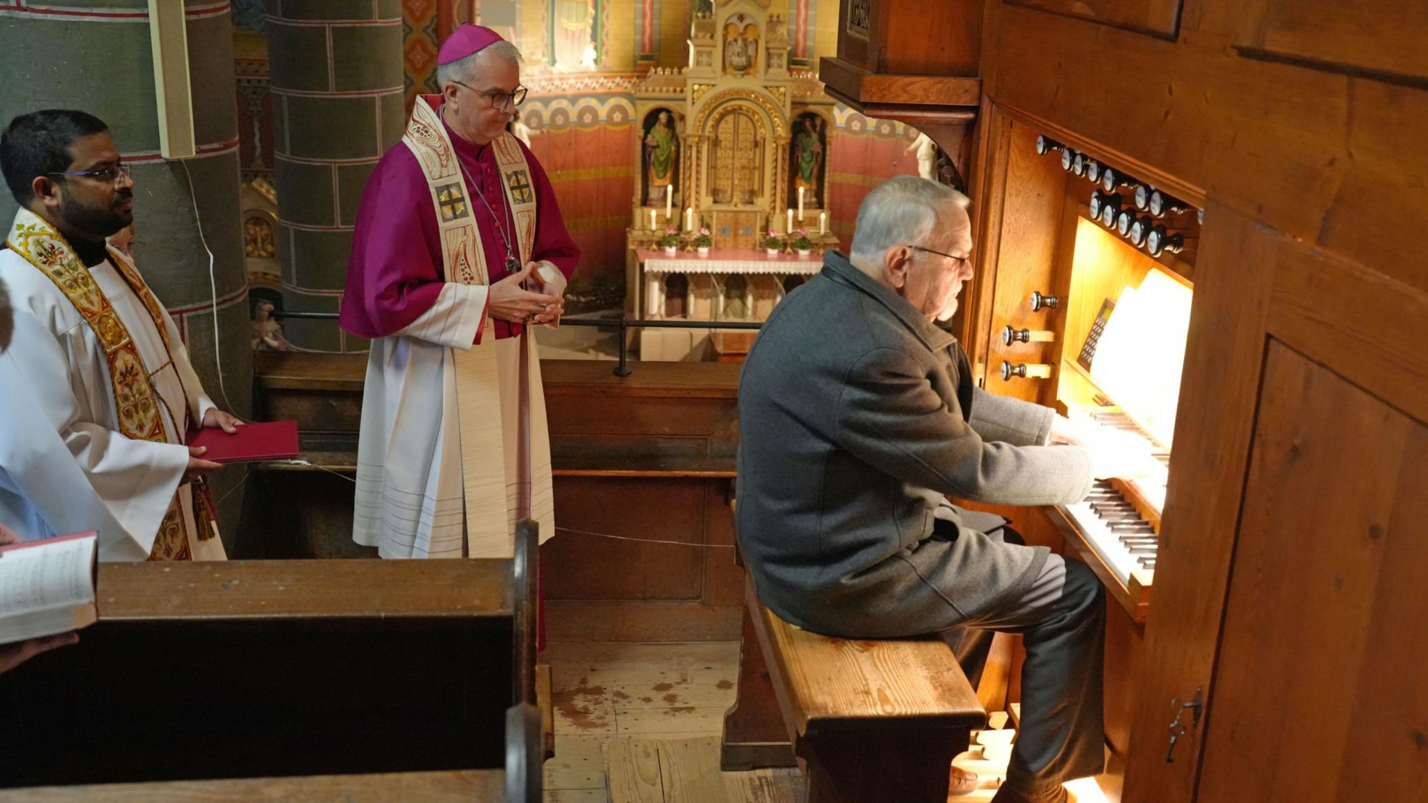 Organist Winfried Hansel spielt zum Auftakt das kleine 'Präludium C-Dur' von Bach. Dahinter stehend Weihbischof Peters und Pfarrer Antony