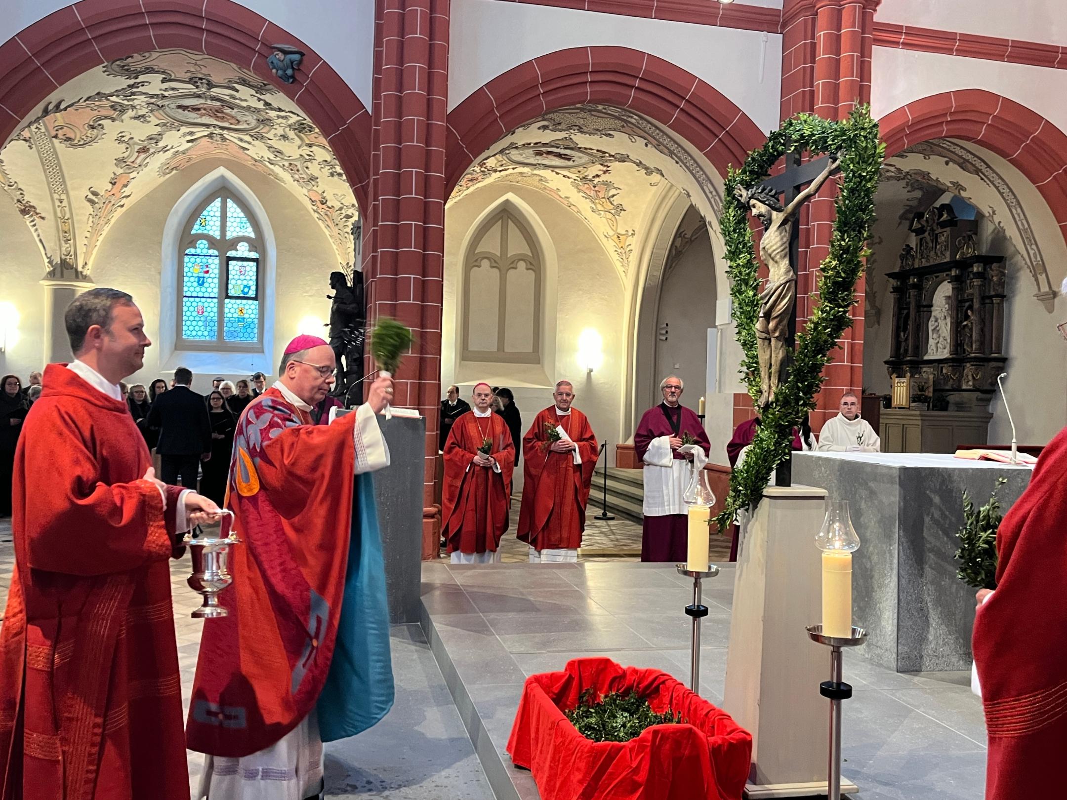 Bischof Ackermann segnet in der Bürgerkirche St. Gangolf die Palmzweige.