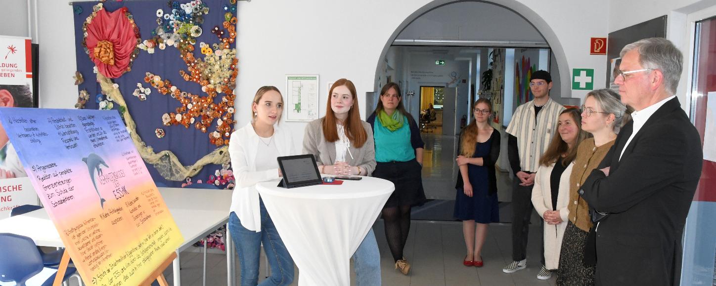 Vivien Schneider und Anna Walle (v. l.) stellen Generalvikar von Plettenberg den Verhaltenskodex der Schule vor.