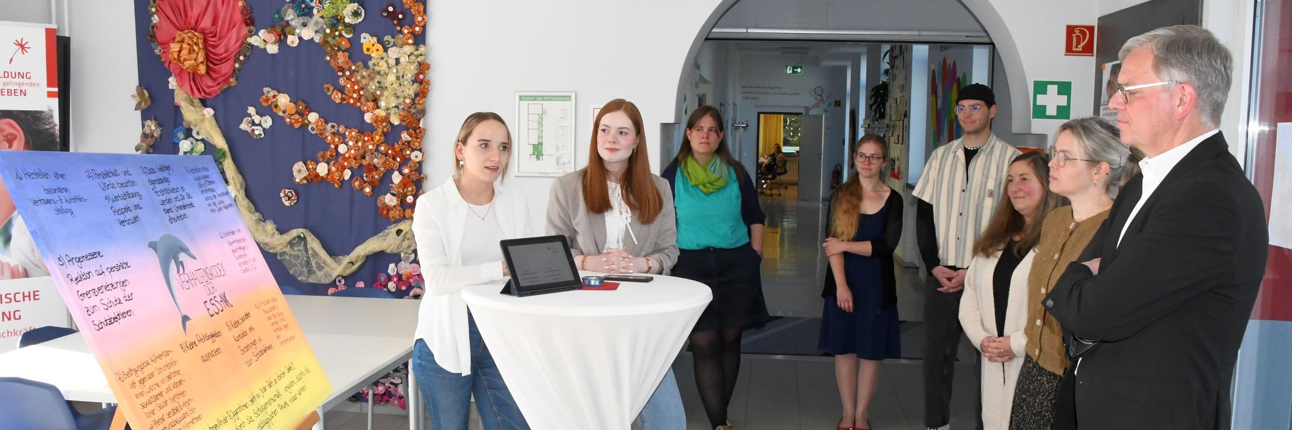Vivien Schneider und Anna Walle (v. l.) stellen Generalvikar von Plettenberg den Verhaltenskodex der Schule vor.