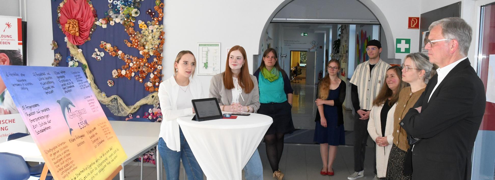Vivien Schneider und Anna Walle (v. l.) stellen Generalvikar von Plettenberg den Verhaltenskodex der Schule vor.