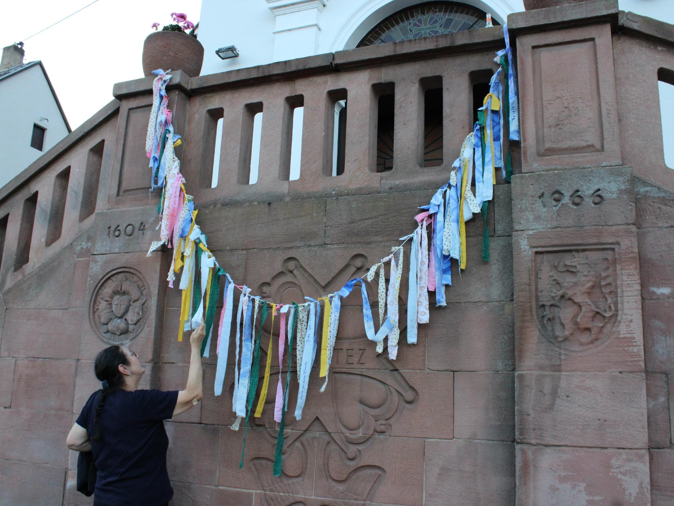 Die Gebetsbänder mit Wünschen für Frieden und Gerechtigkeit wurden an der Treppe der Hugenottenkirche aufgehängt. Foto: evks/Eulenstein