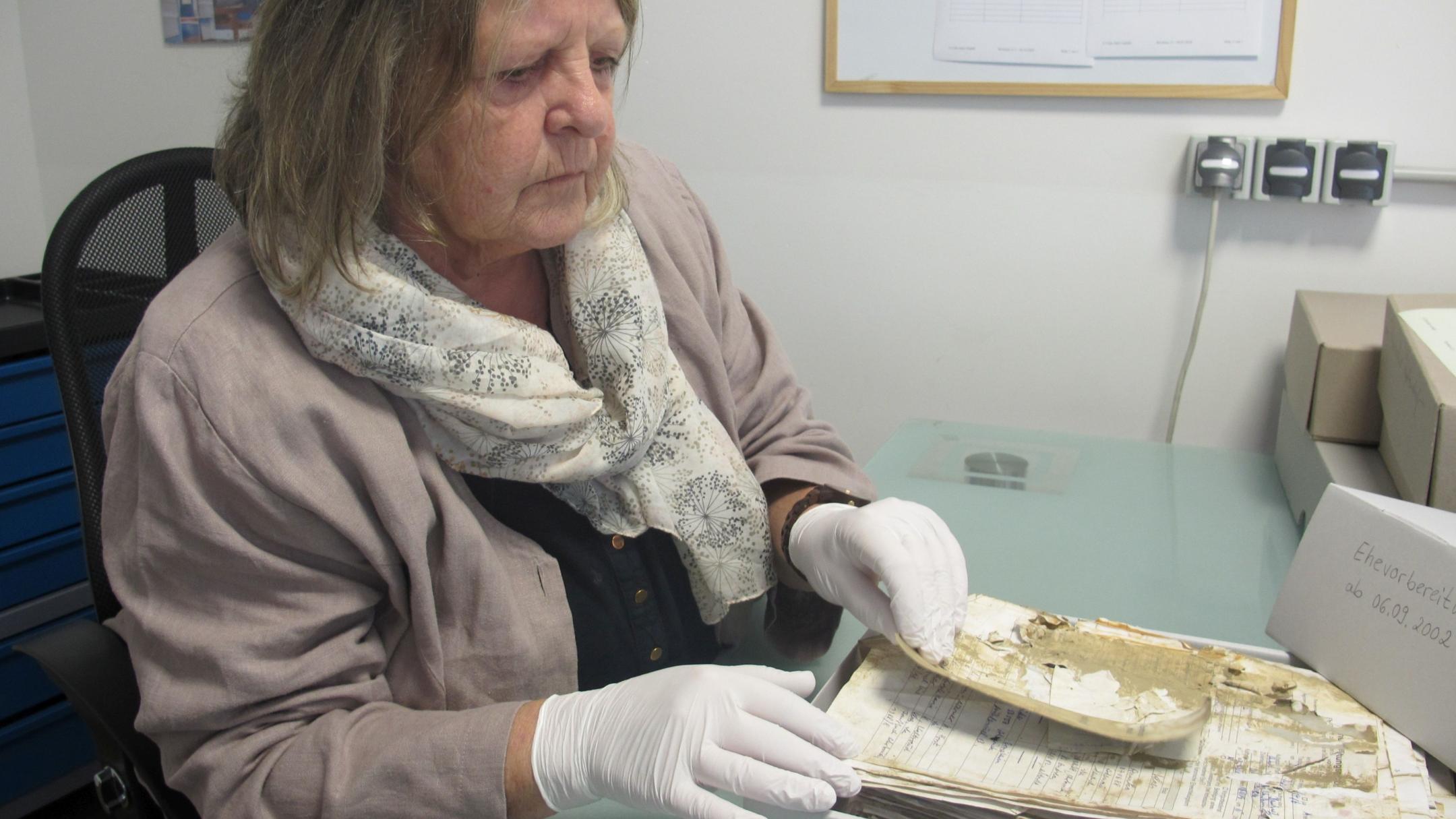 Christa Schäfer, Leiterin der Club Aktiv GmbH Akten- & Buch-Erhaltung, prüft die getrockneten Unterlagen aus dem Pfarrarchiv in Mettendorf. (Fotos: Stefan Schneider/Bistum Trier)