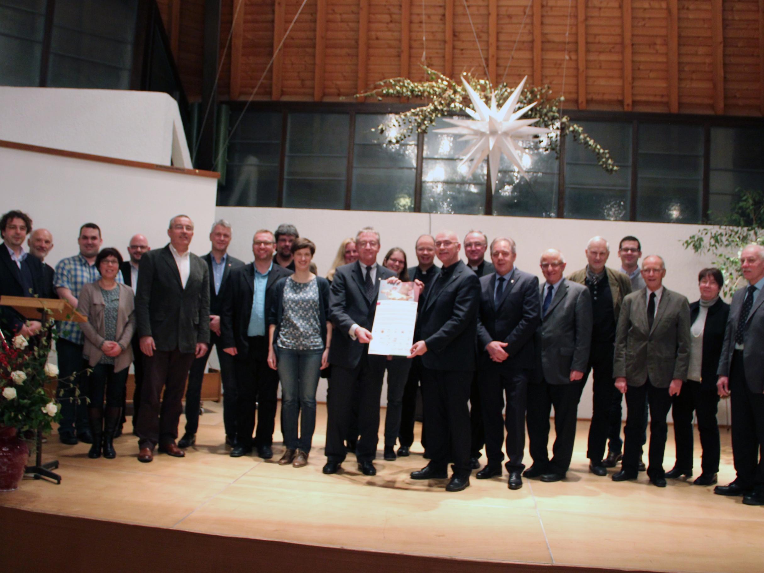 Die Projektpartner und Bischof Ackermann (mitte) mit dem unterschriebenen Leitwort.