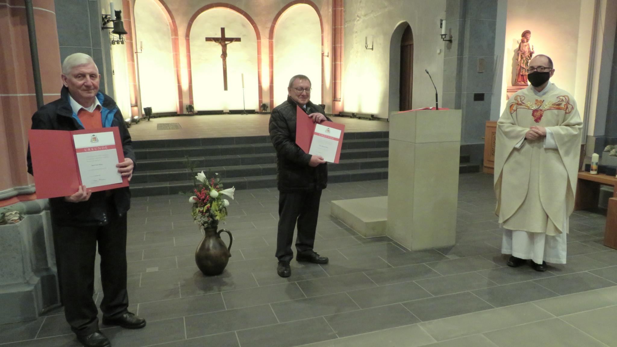 Pfarrer Augustinus Jünemann (rechts) überreicht Carl Woog (links) und Reimund Kerner die Dankesurkunde des Bistums Trier. Foto: Heinz-Walter Lautz