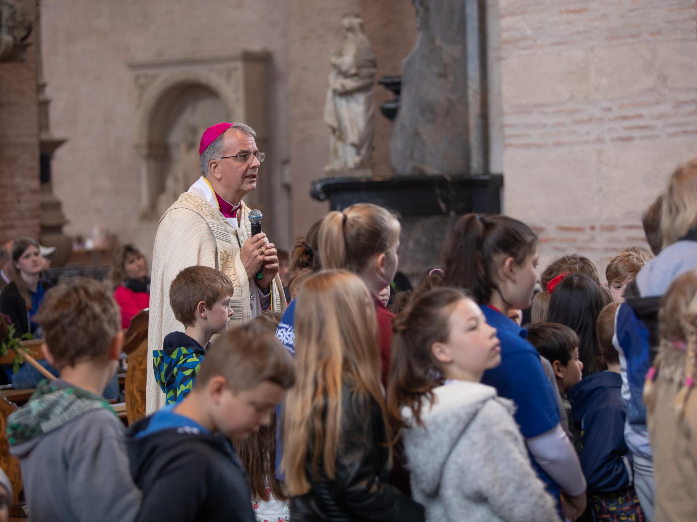 Weihbischof Peters und die Kinder betrachten zusammen das Kreuz.