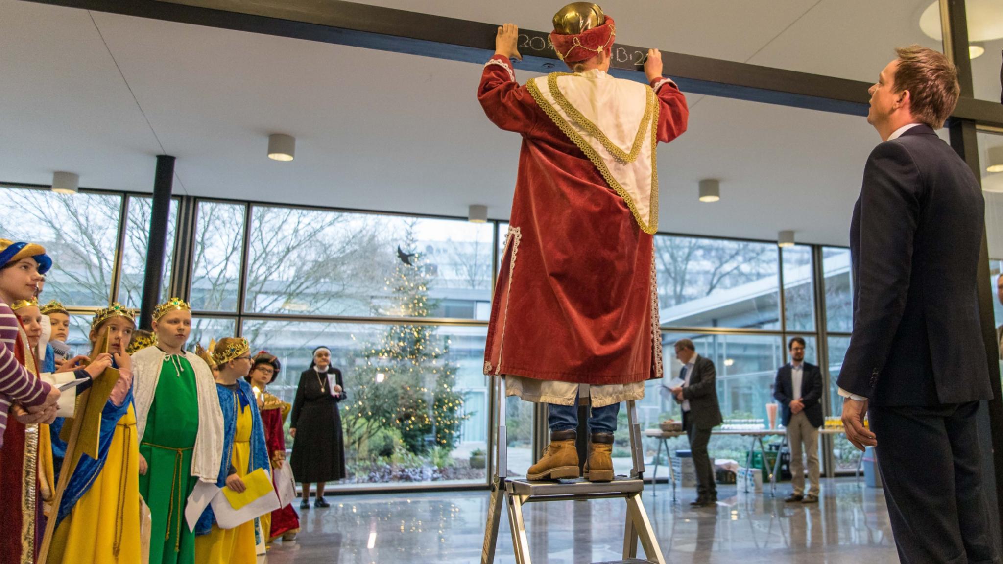 Ein Sternsinger beim Schreiben des Segens (Quelle: Staatskanzlei Saarland)