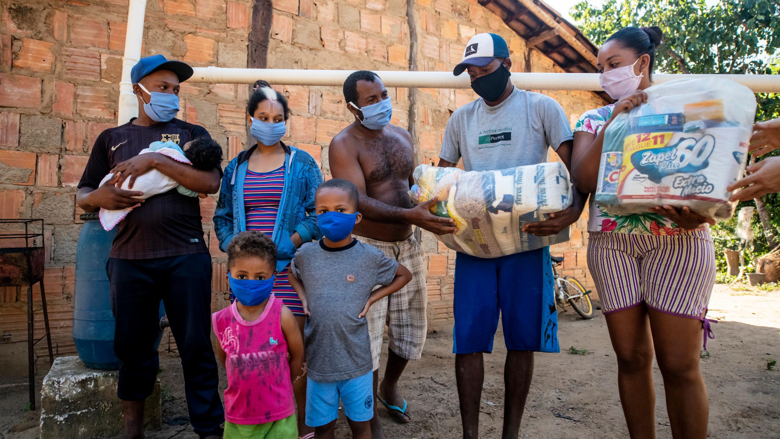 Eine brasilianische Familie mit Schutzmasken, Lebensmittelpaket und Hygieneartikeln, die sie von der CPP im Rahmen der Corona-Soforthilfe erhalten hat (Foto: Adveniat)