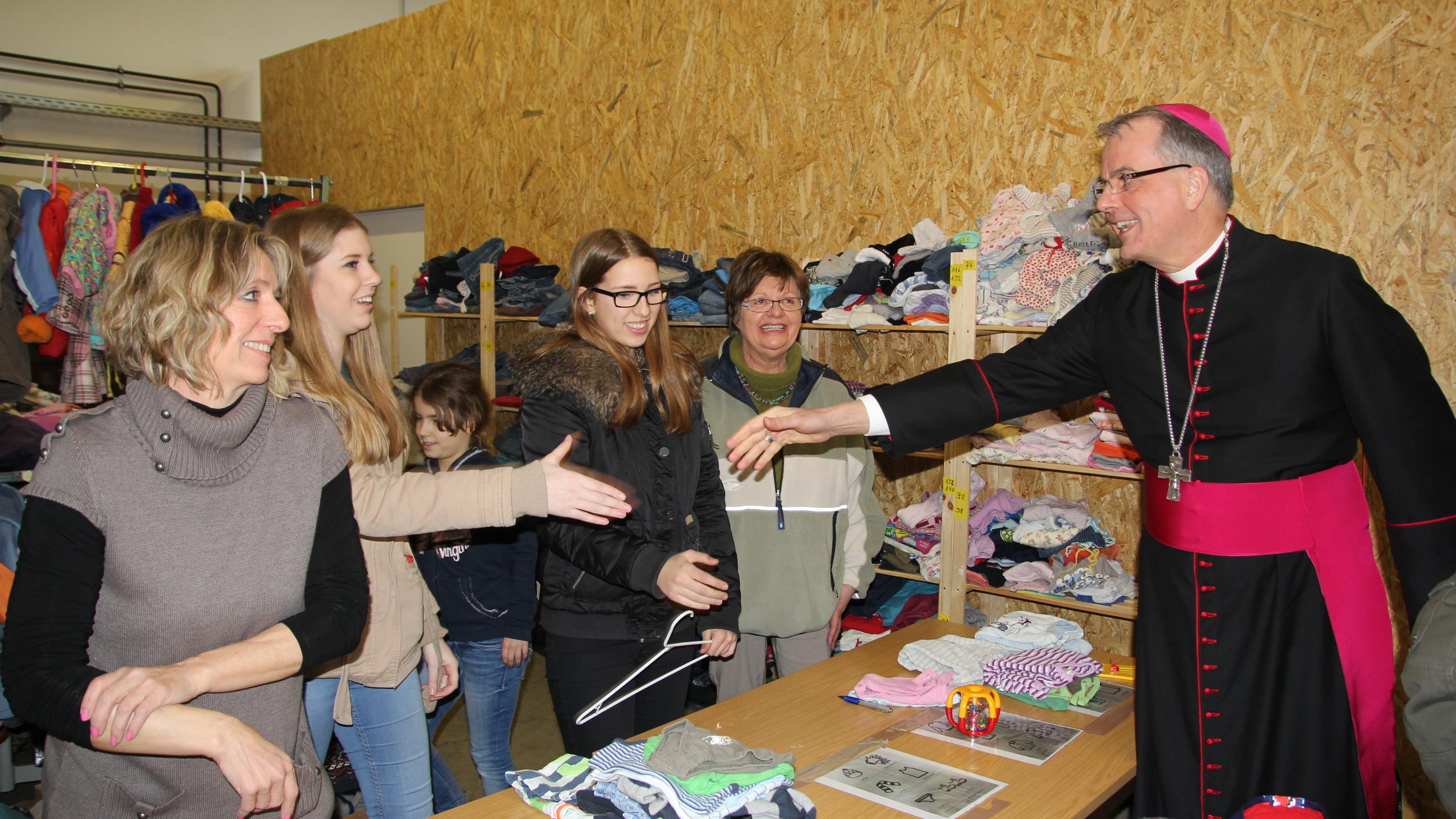 Weihbischof Peters hat die Ehrenamtlichen getroffen, die sich in der Kleiderkammer seit Monaten für Flüchtlinge engagieren.