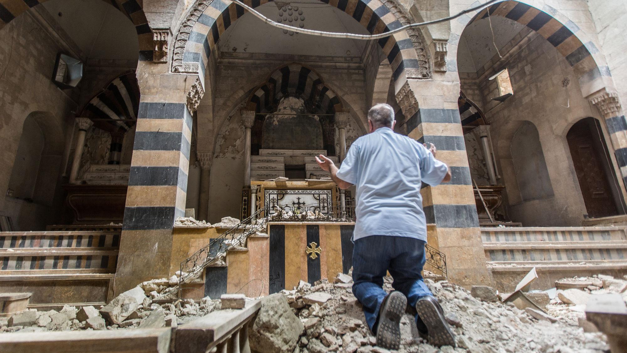 Ein Mann betet in einer zerstörten Kirche in Syrien