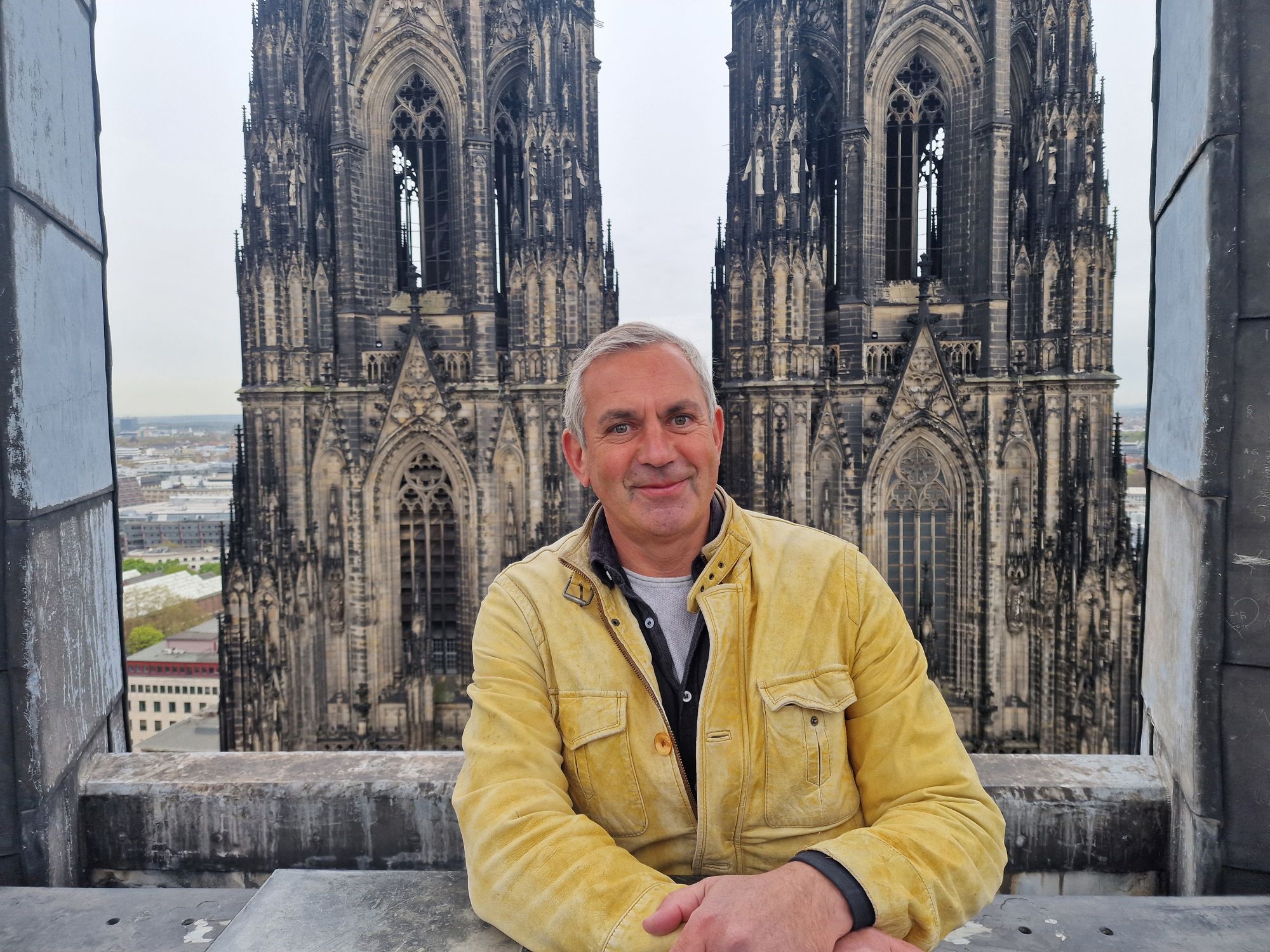 Ein Mann in gelber Jacke steht vor einer Kirche