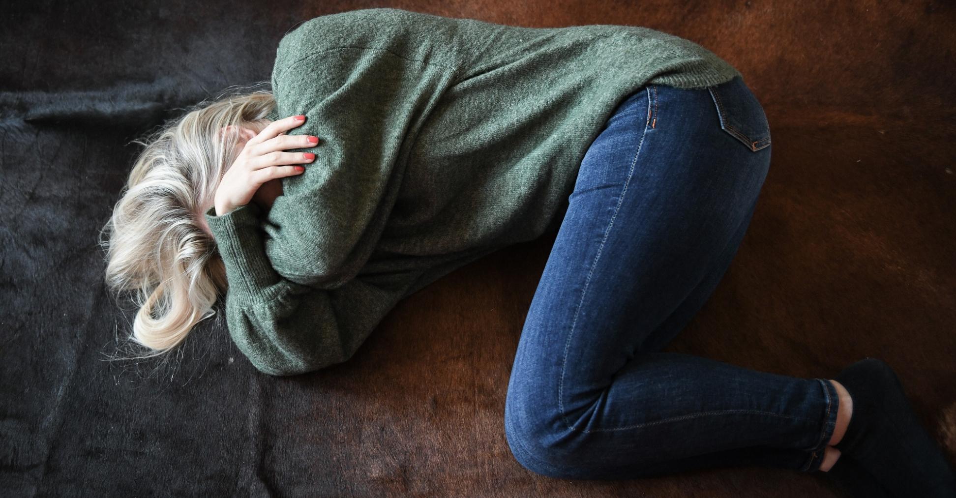 Eine Frau liegt zusammengekauert auf dem Boden.