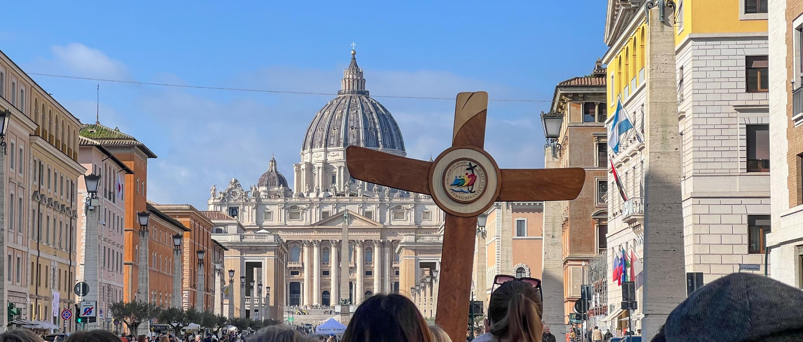 Eine deutsche Gruppe ist mit Pilgerkreuz unterwegs auf der Via della Conciliazione in Rom zum Petersdom.