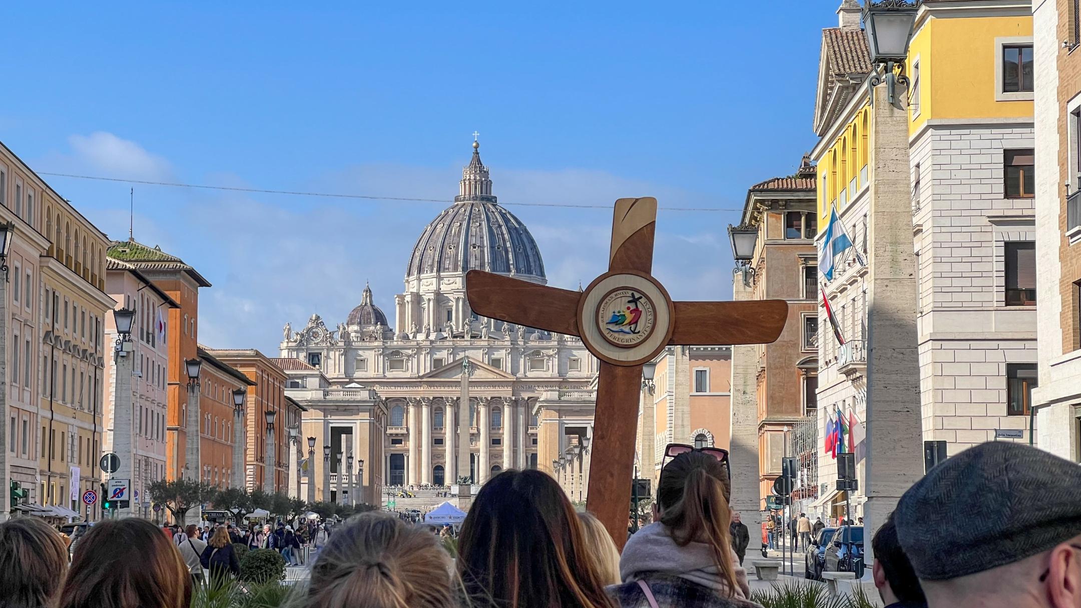 Eine deutsche Gruppe ist mit Pilgerkreuz unterwegs auf der Via della Conciliazione in Rom zum Petersdom.