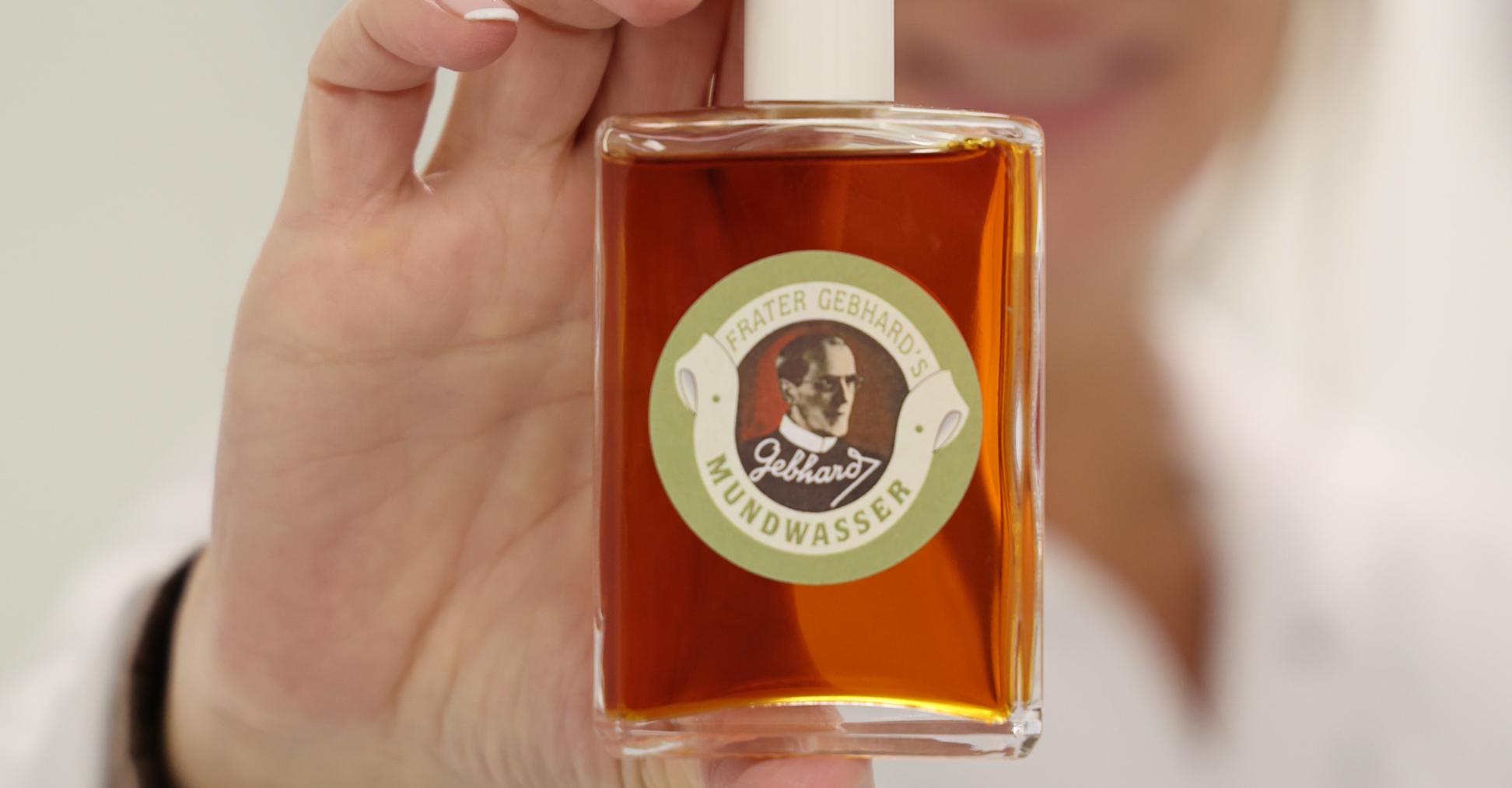 Eine Frau hält eine Flasche mit bräunlicher Flüssigkeit in die Kamera