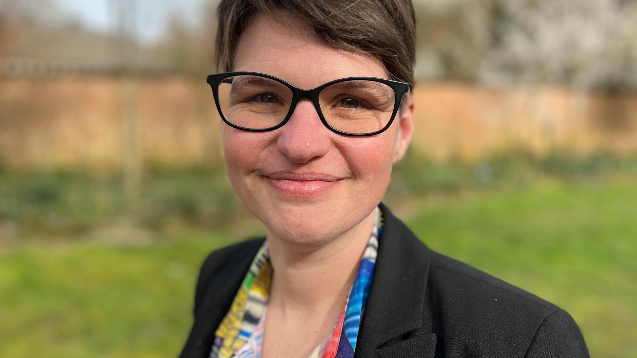 Eine Frau mit Brille lächelt in die Kamera
