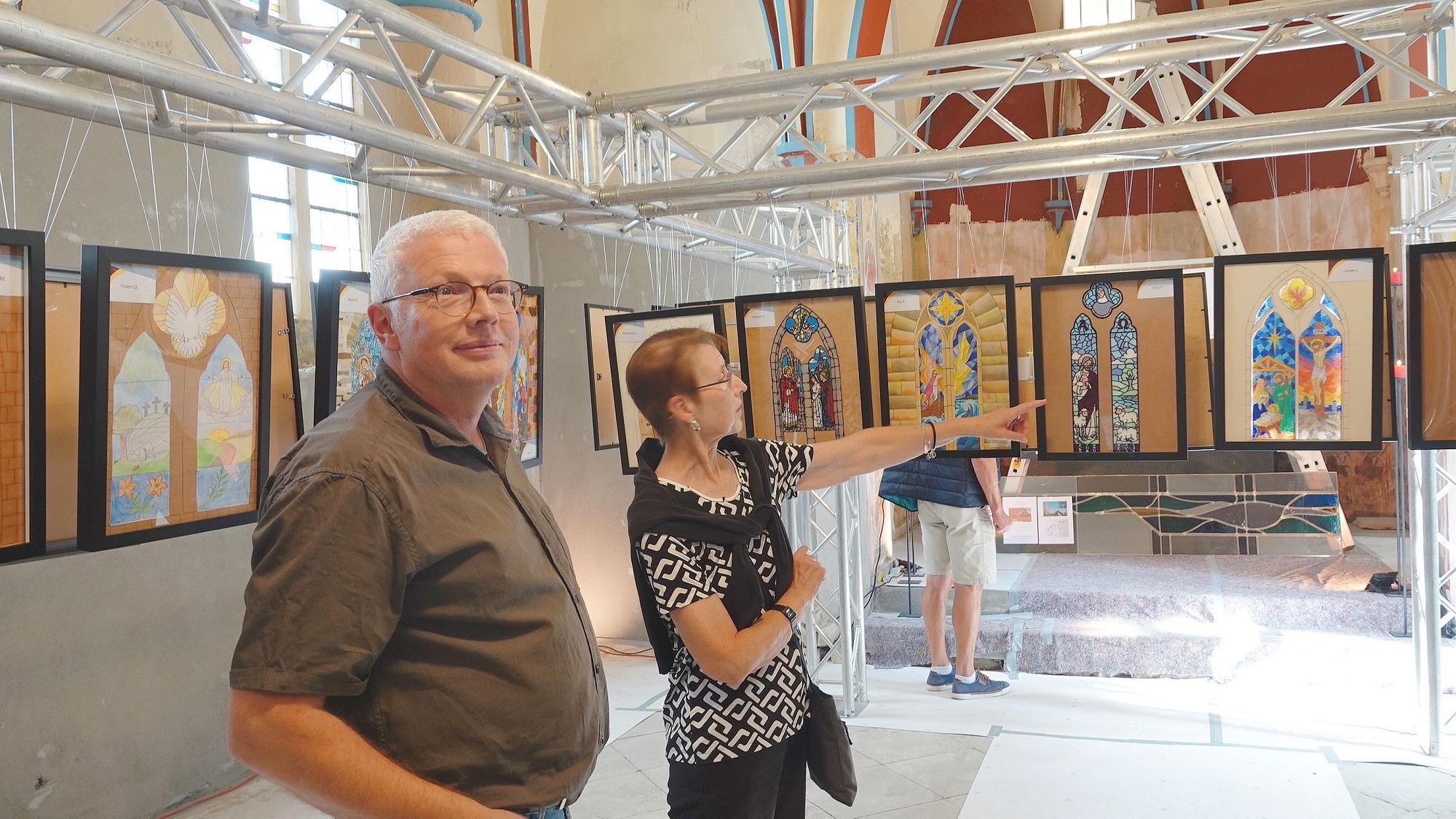 Im noch immer nicht flutsanierten „Hemmessener Dom“ schaut sich Markus Hartmann zusammen mit  einer Besucherin die Ideen der Zwölftklässler zur Fenstergestaltung an.