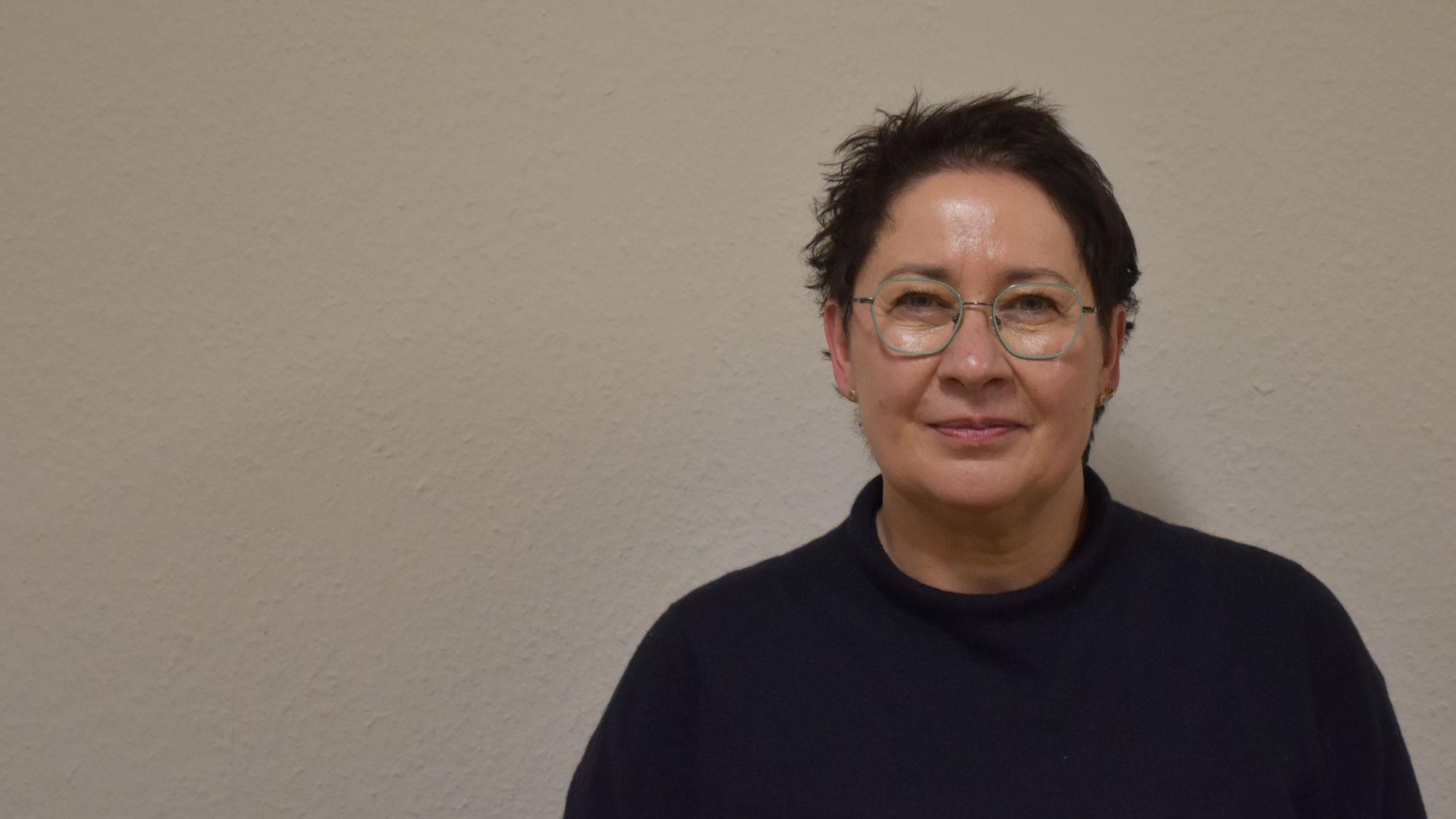 Eine Frau mit kurzen schwarzen Haaren blickt in die Kamera