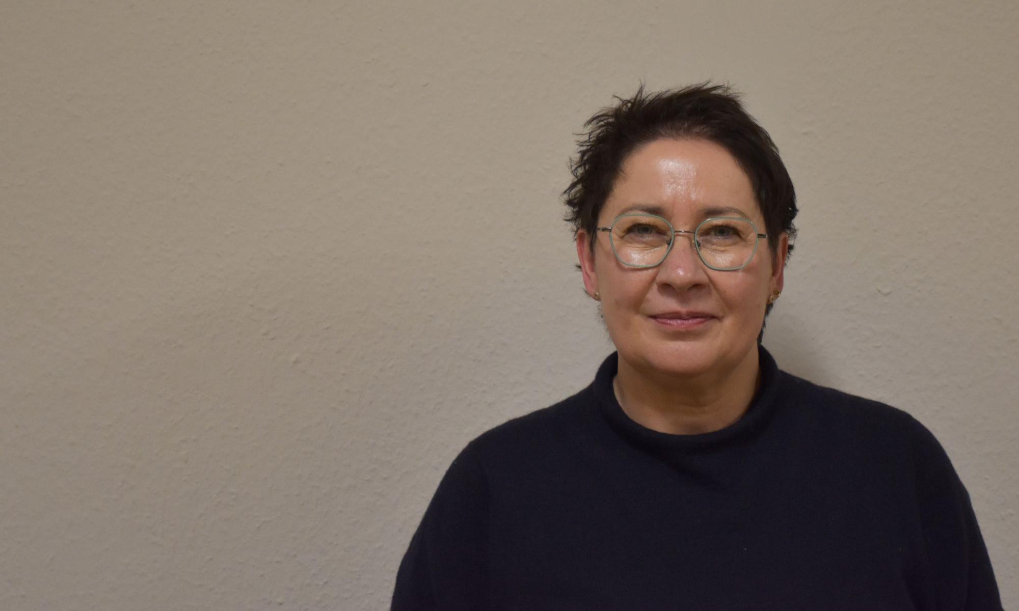 Eine Frau mit kurzen schwarzen Haaren blickt in die Kamera