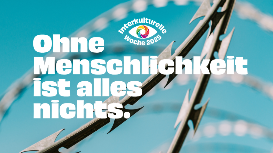 Im Hintergrund ist ein Stacheldrahtzaun zu sehen, im Vordergrund steht: 'Ohne Menschlichkeit ist alles nichts.'