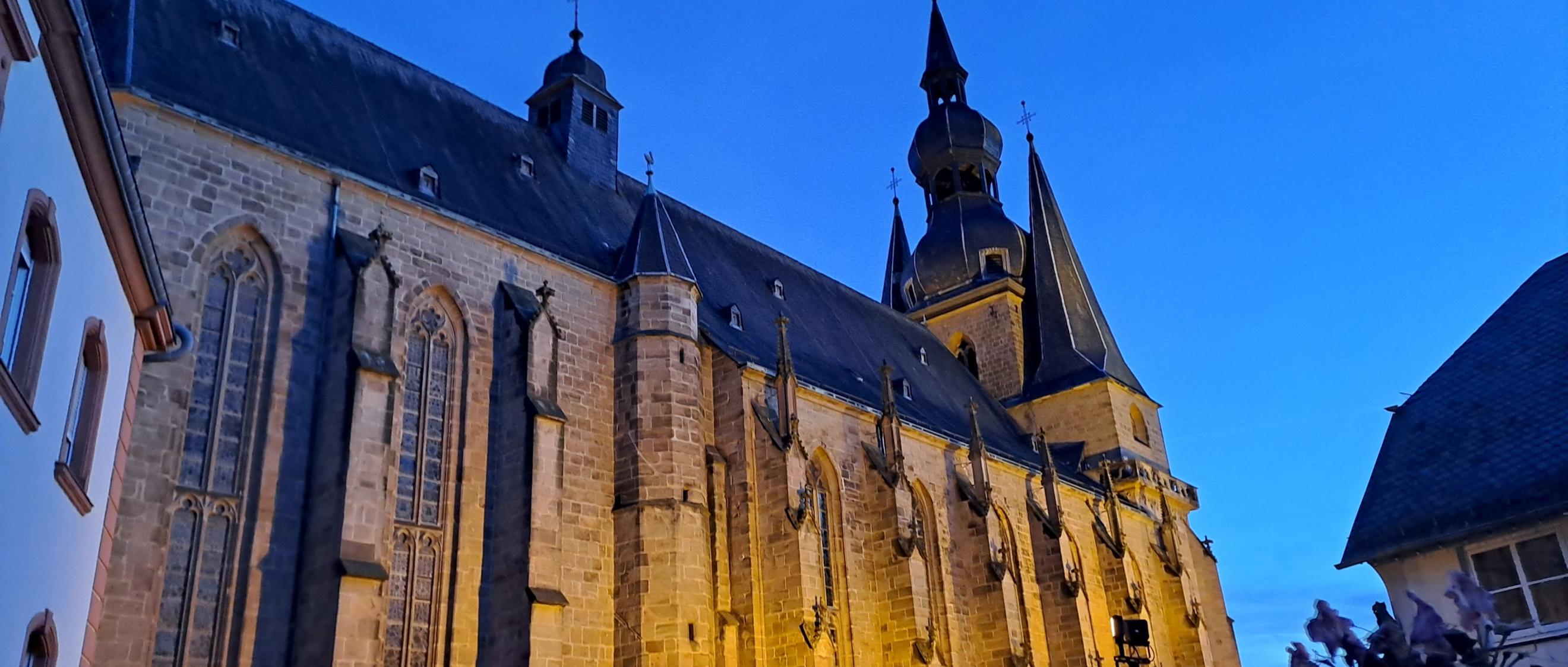 Große beleuchtete Kirche in der Abenddämmerung vor blauem Himmel
