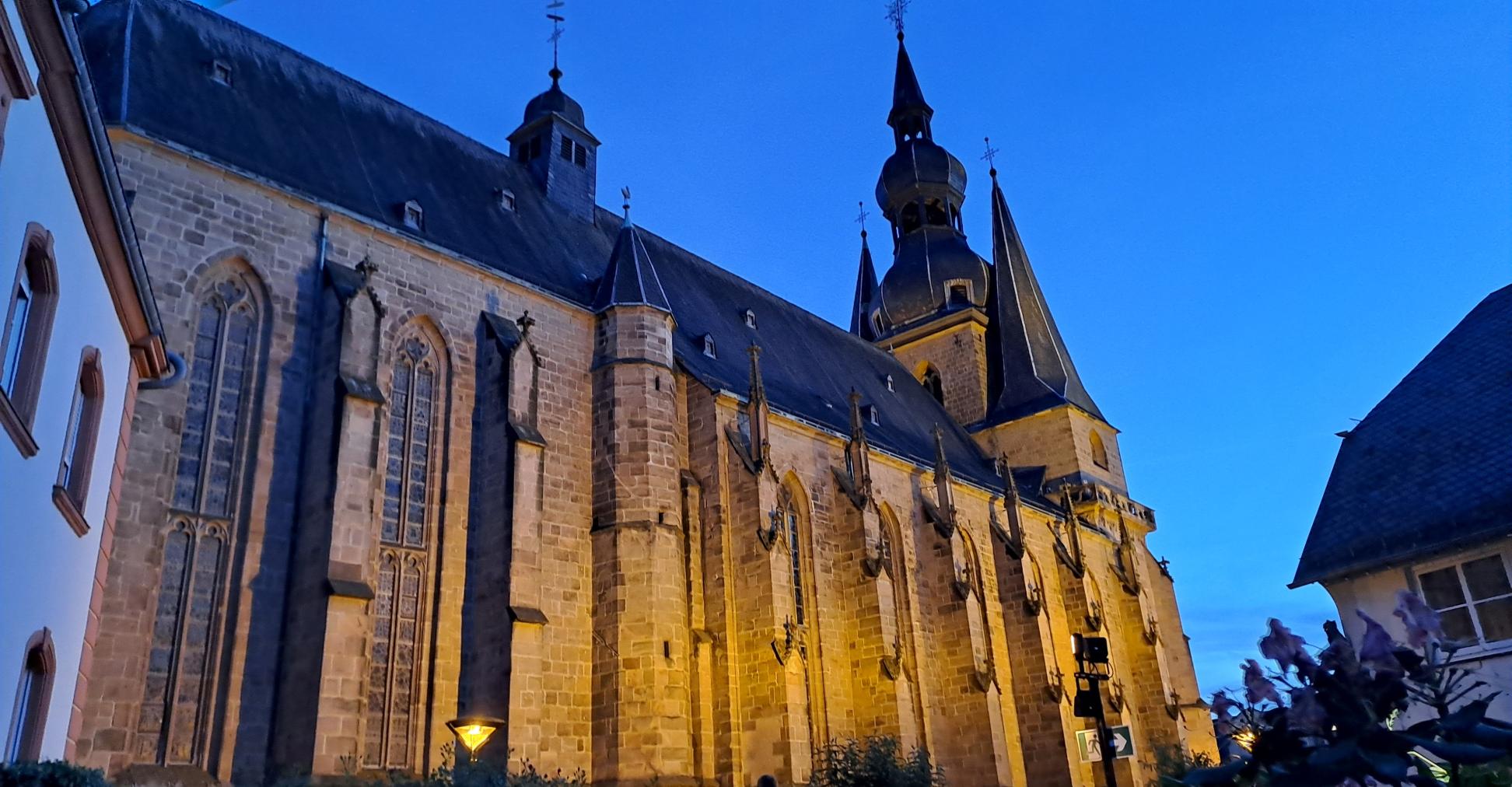 Große beleuchtete Kirche in der Abenddämmerung vor blauem Himmel