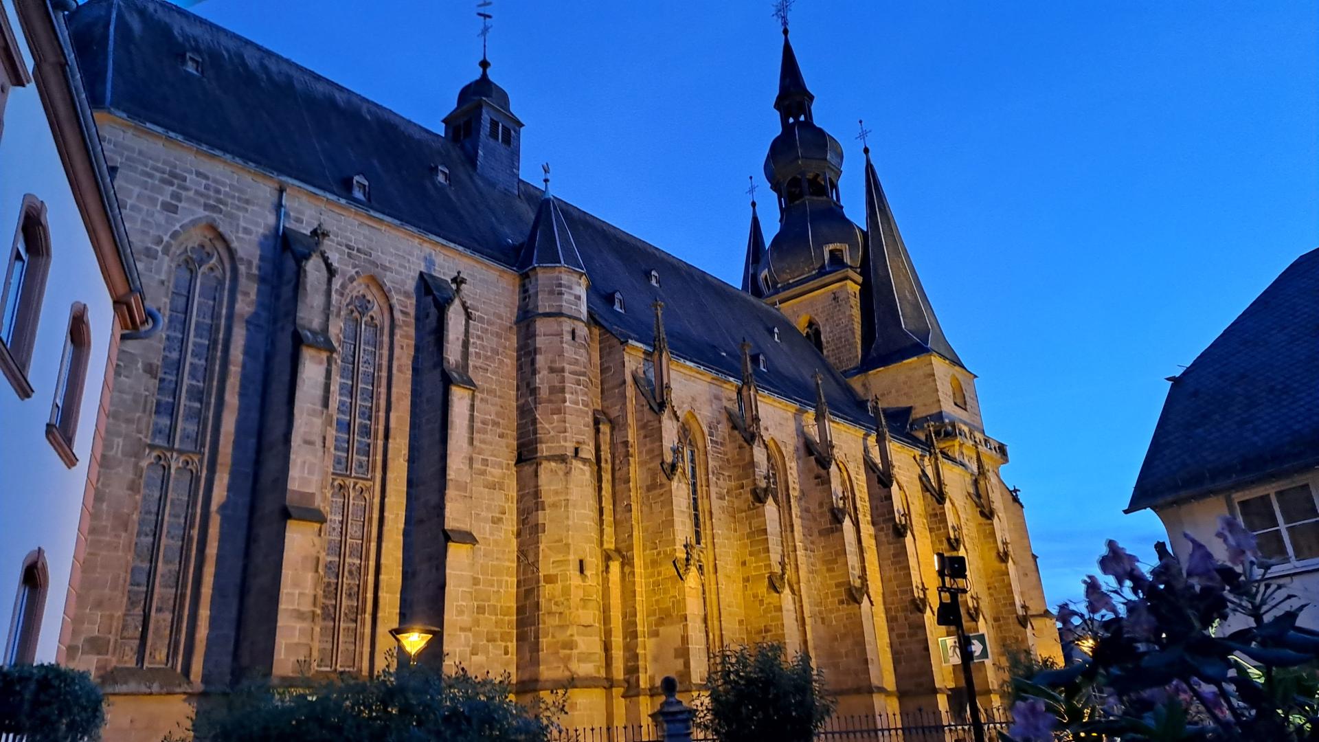 Große beleuchtete Kirche in der Abenddämmerung vor blauem Himmel