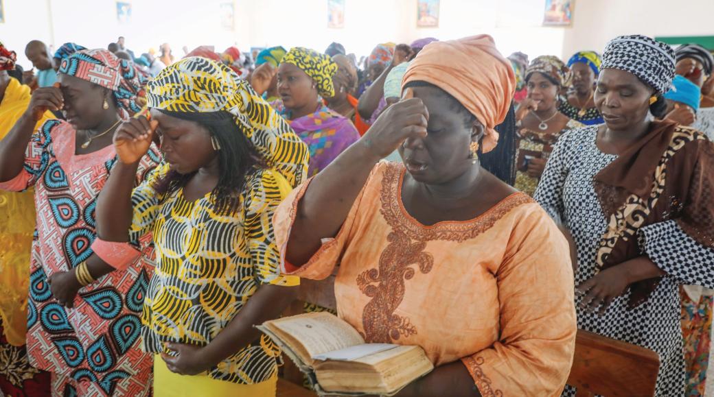 Betende nigerianische Frauen in traditionellen bunten Gewändern