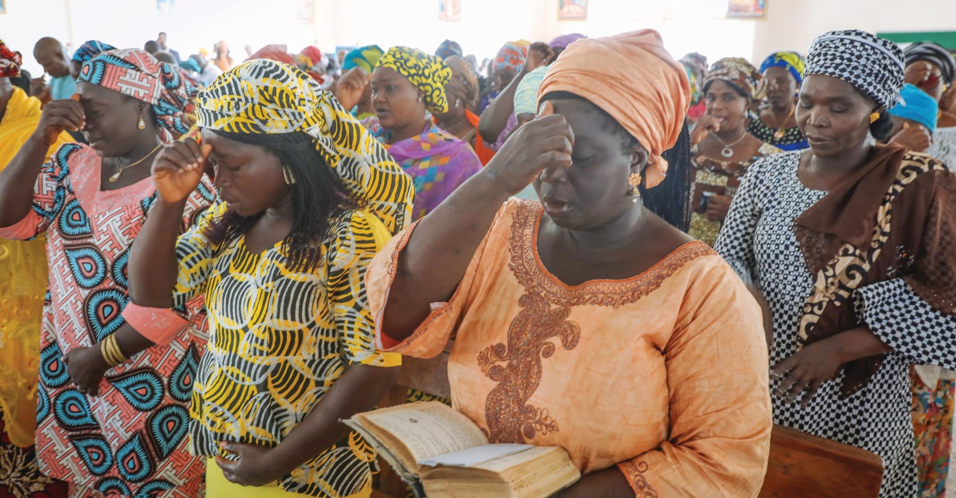 Betende nigerianische Frauen in traditionellen bunten Gewändern