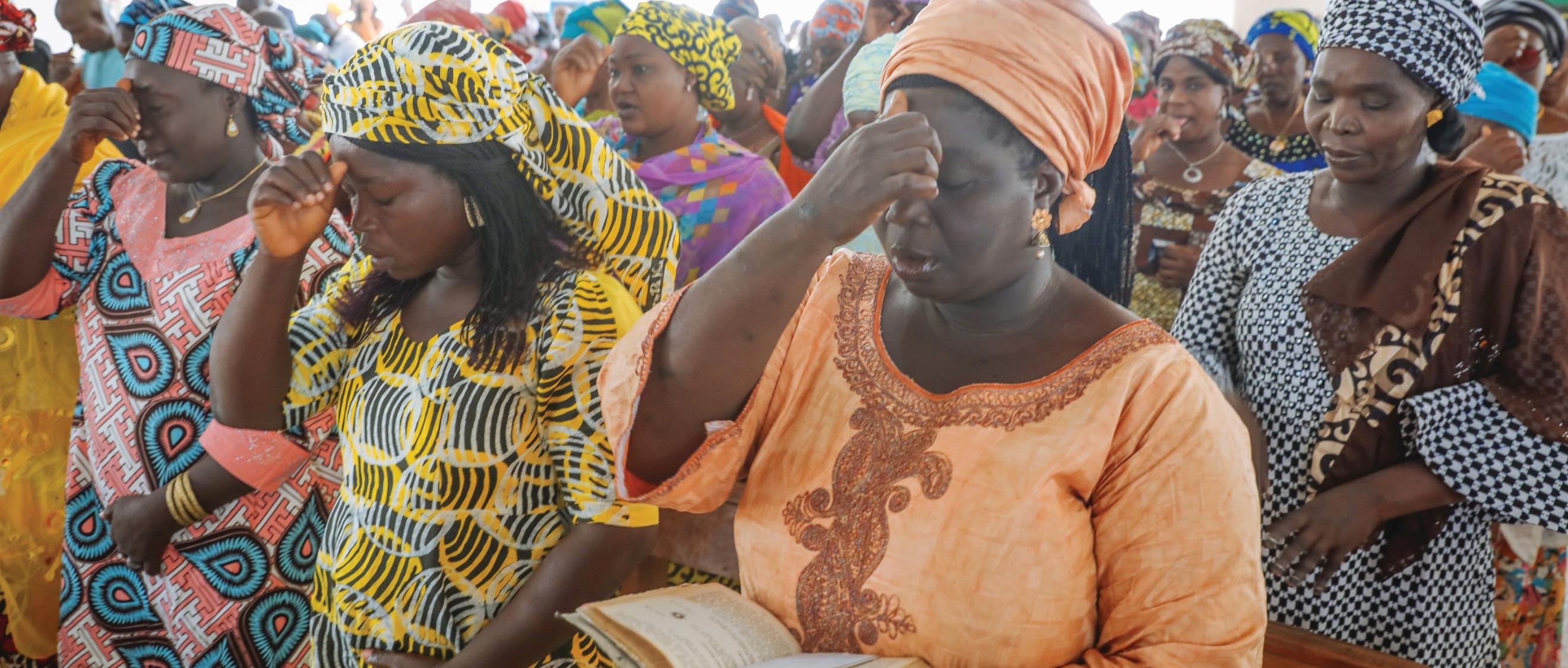 Betende nigerianische Frauen in traditionellen bunten Gewändern