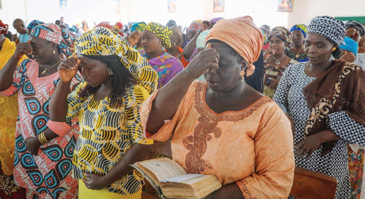 Betende nigerianische Frauen in traditionellen bunten Gewändern