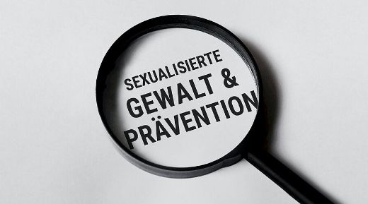 Man sieht eine Lupe mit dem Text 'Sexualisierte Gewalt & Prävention'