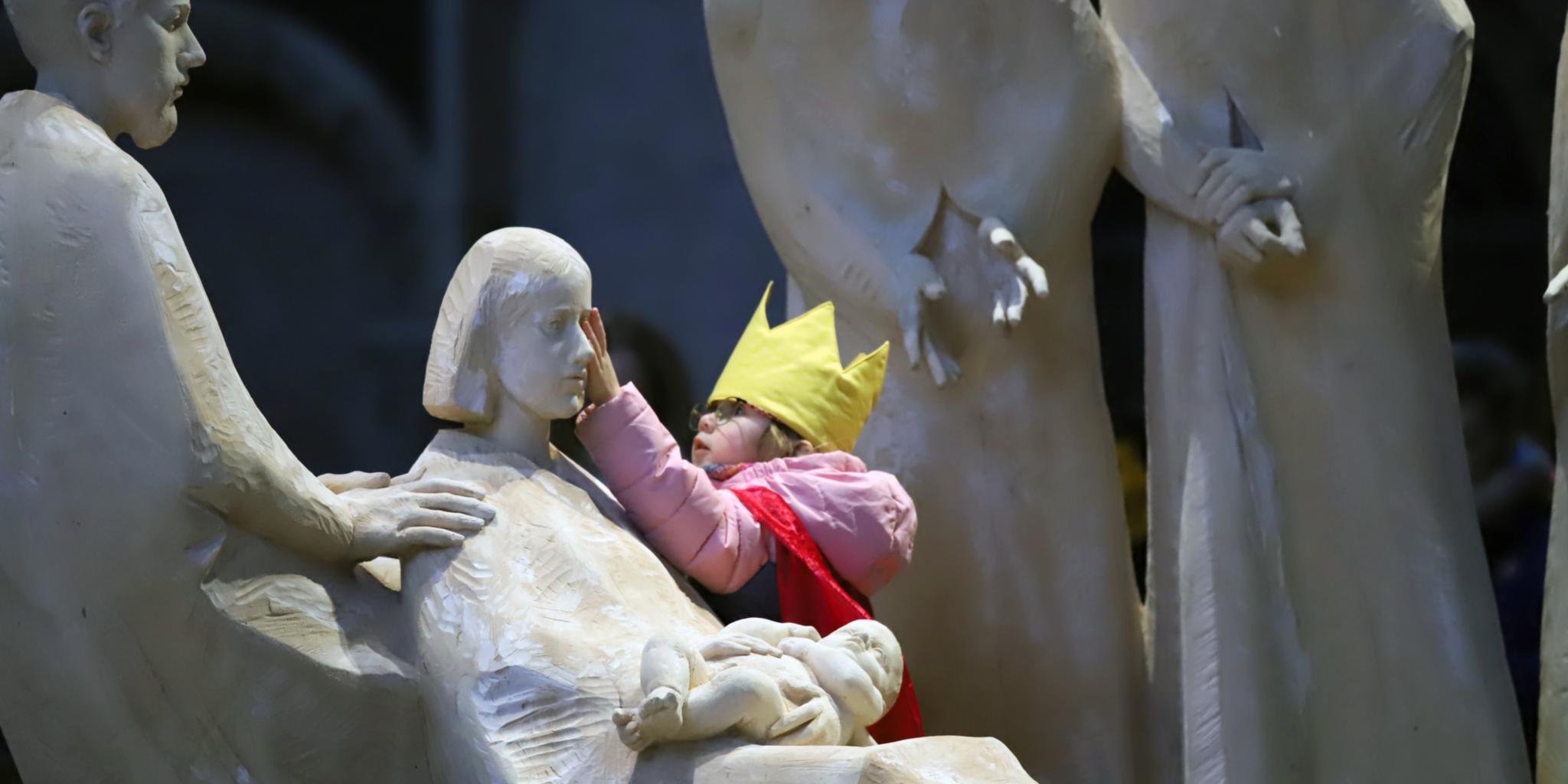 Eine Sternsingerin berührt Maria in der Krippe im Trierer Dom