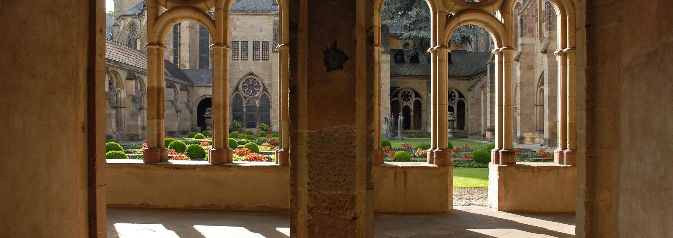 Blick durch zwei Torbögen in den Kreuzgang des Trierer Doms und in den Garten.