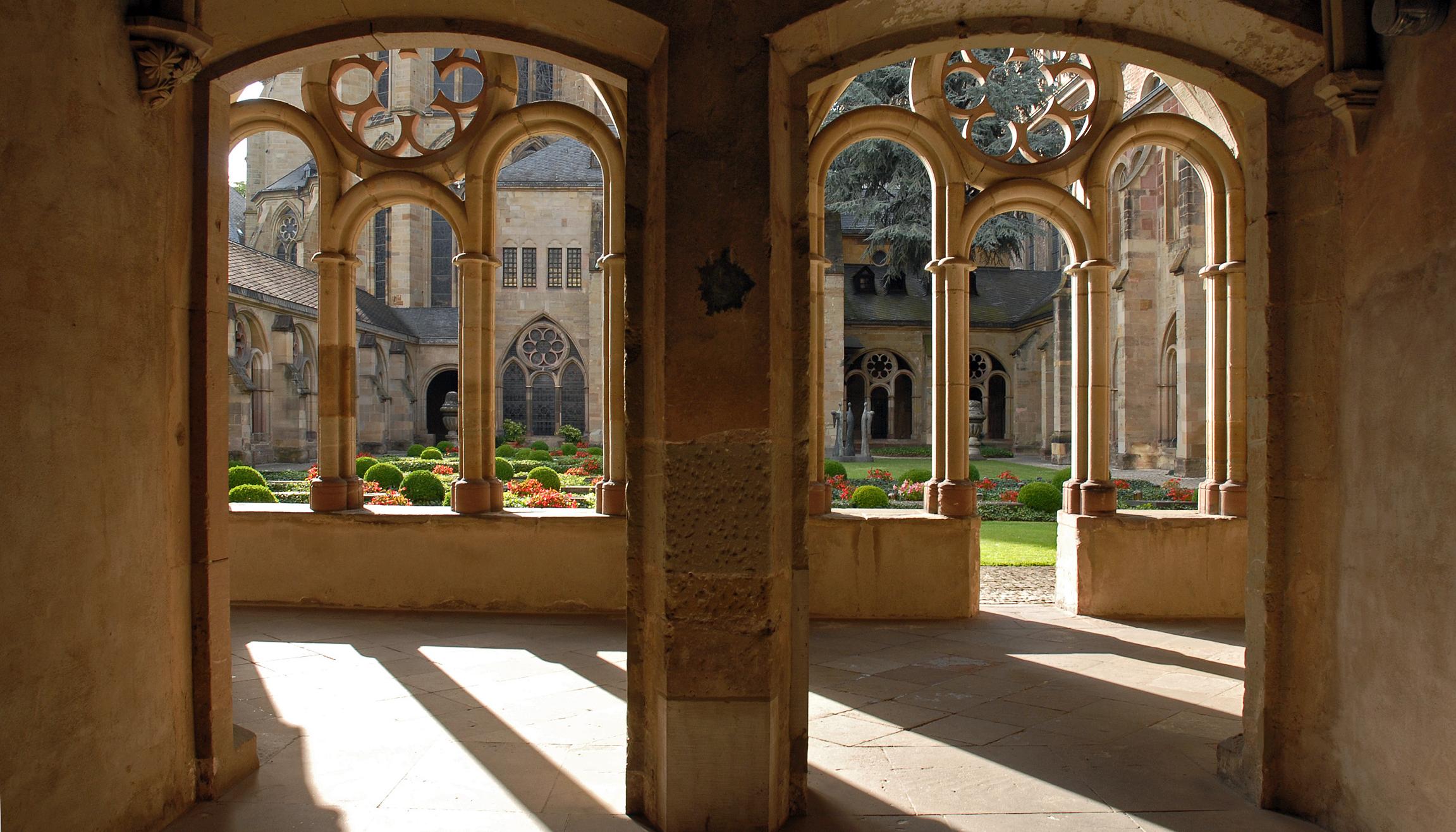 Blick durch zwei Torbögen in den Kreuzgang des Trierer Doms und in den Garten.