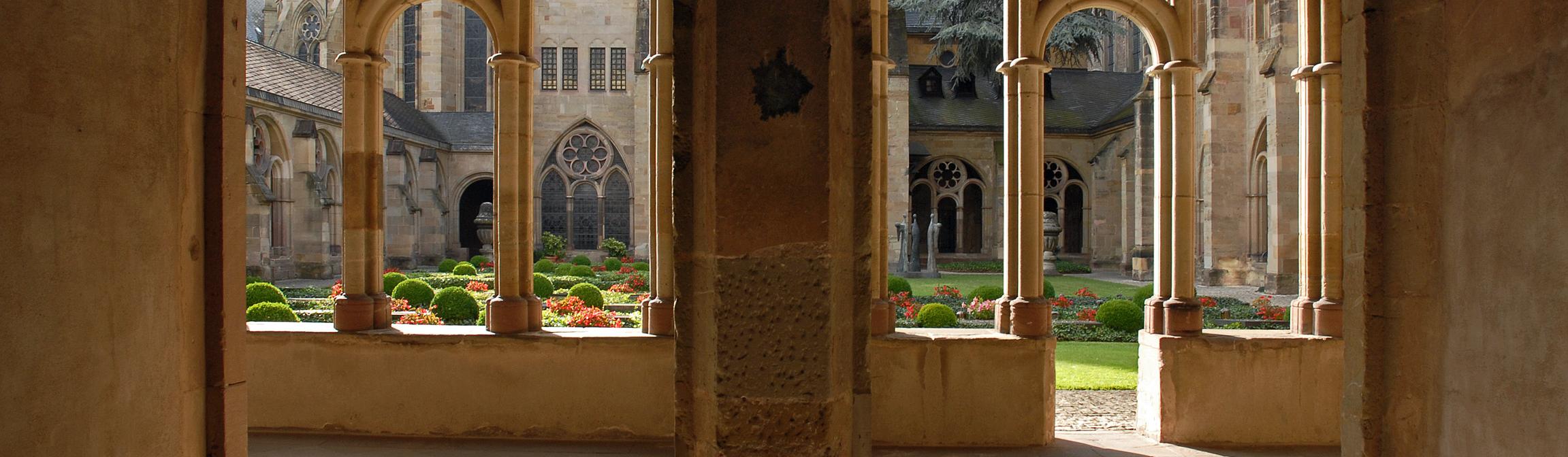 Blick durch zwei Torbögen in den Kreuzgang des Trierer Doms und in den Garten.