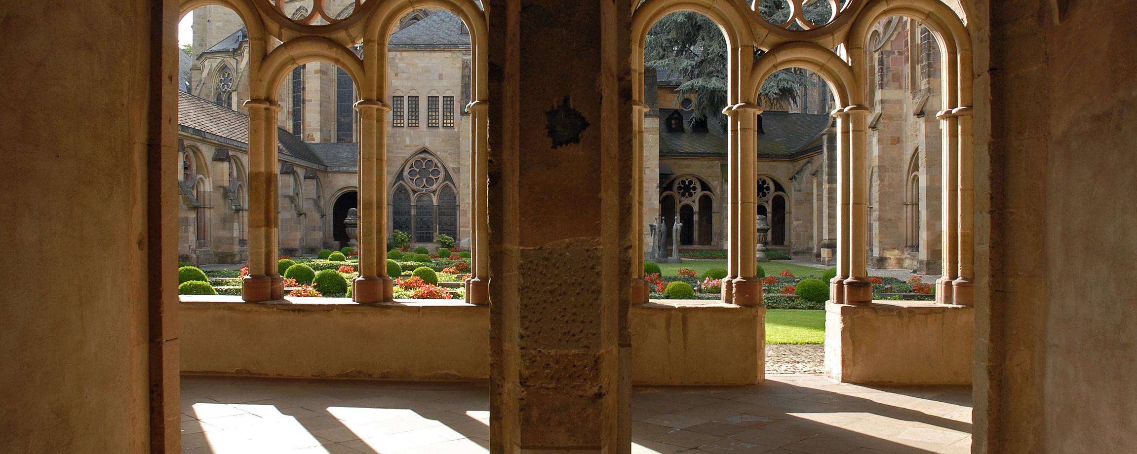 Blick durch zwei Torbögen in den Kreuzgang des Trierer Doms und in den Garten.