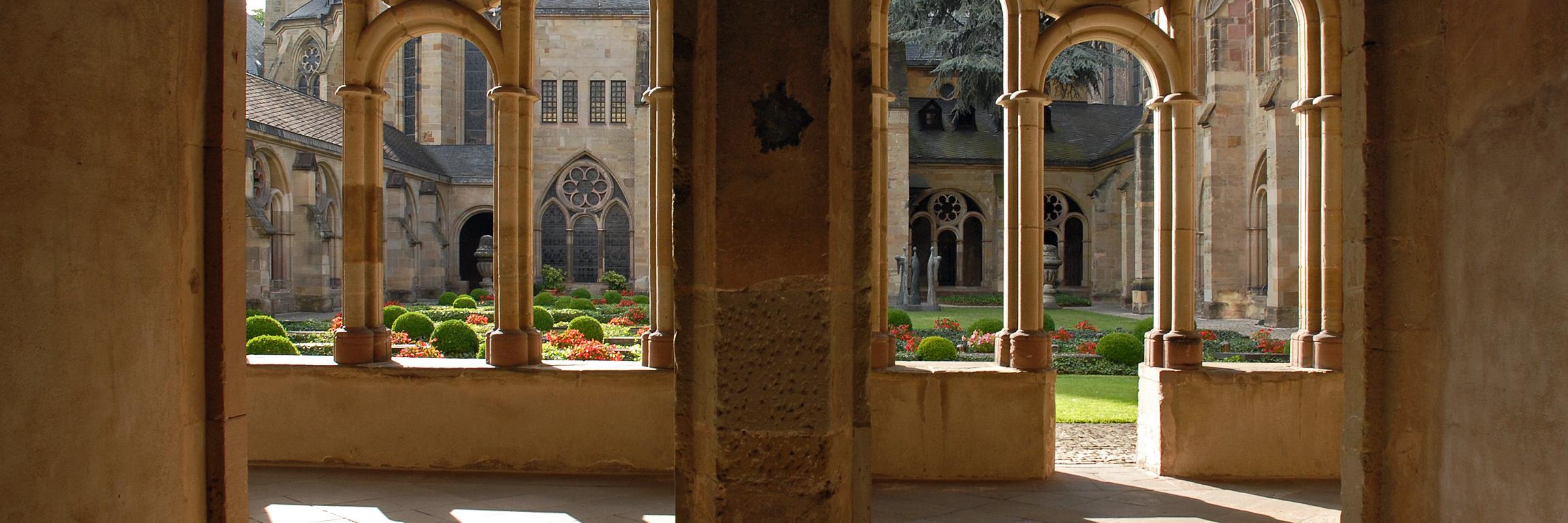 Blick durch zwei Torbögen in den Kreuzgang des Trierer Doms und in den Garten.