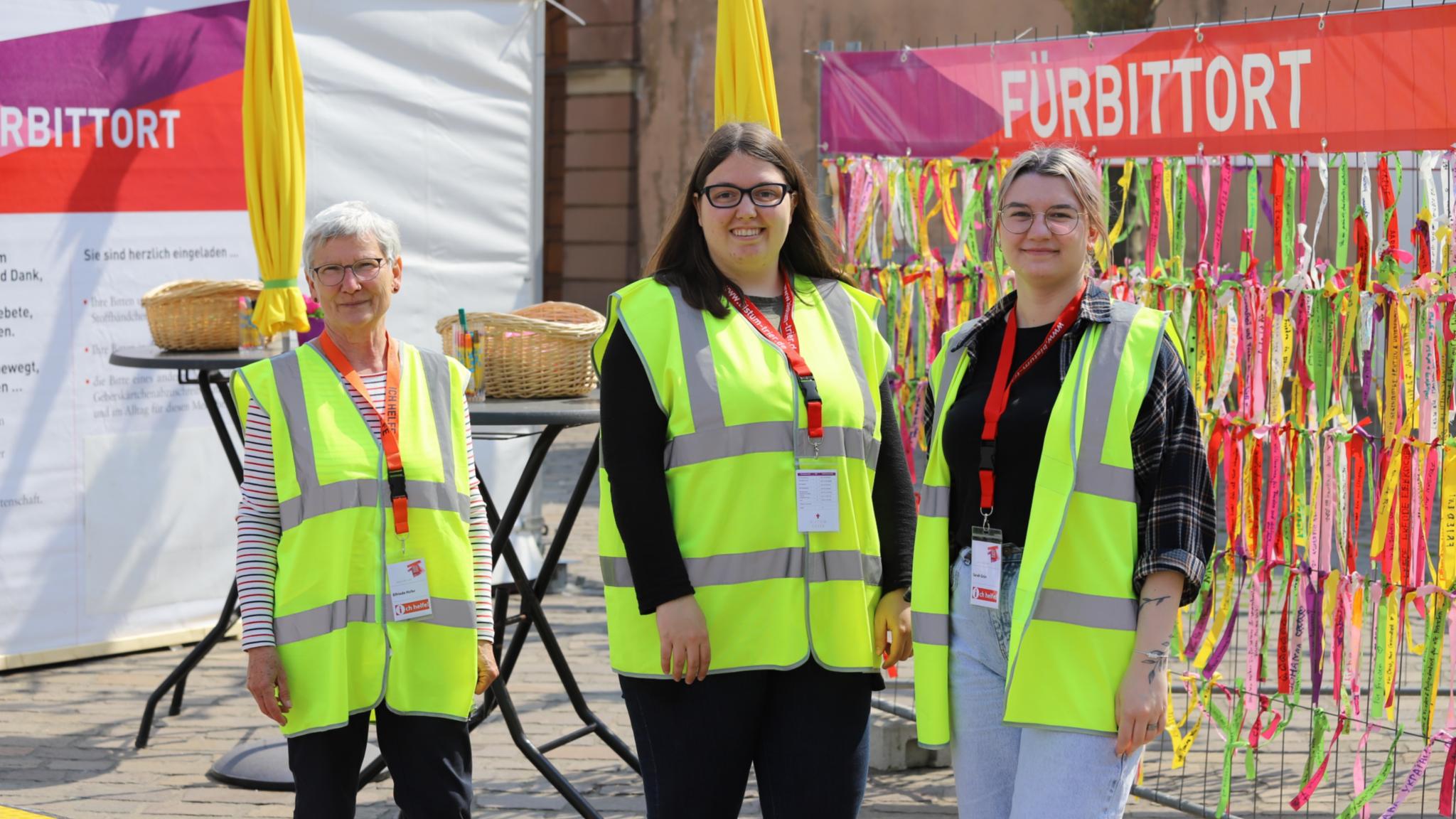 drei Frauen mit Warnwesten stehen vor dem Fürbittort der Heilig-Rock-Tage