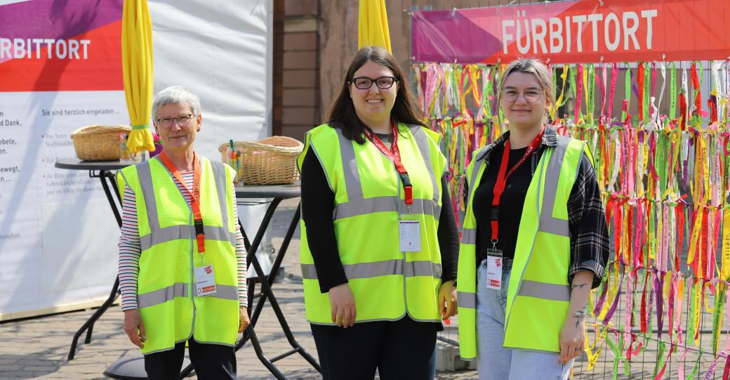 drei Frauen mit Warnwesten stehen vor dem Fürbittort der Heilig-Rock-Tage