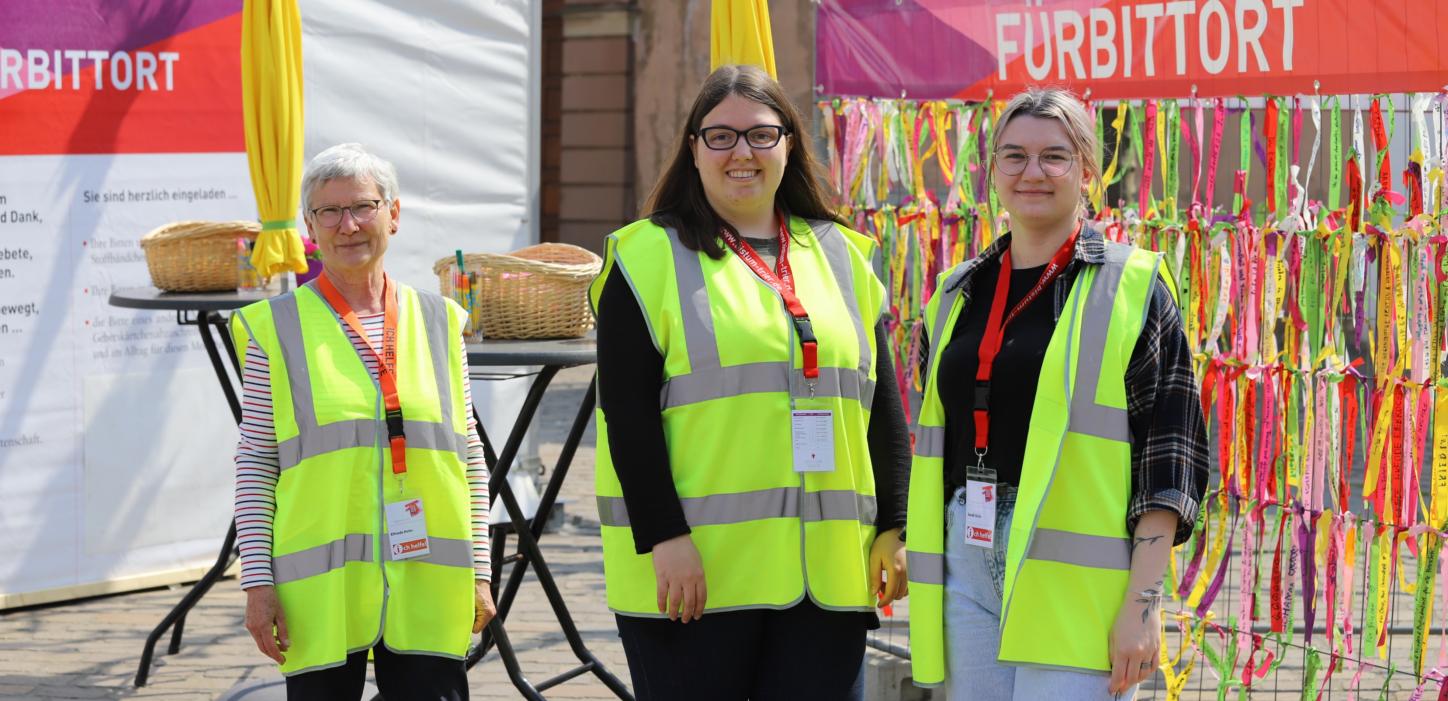 drei Frauen mit Warnwesten stehen vor dem Fürbittort der Heilig-Rock-Tage